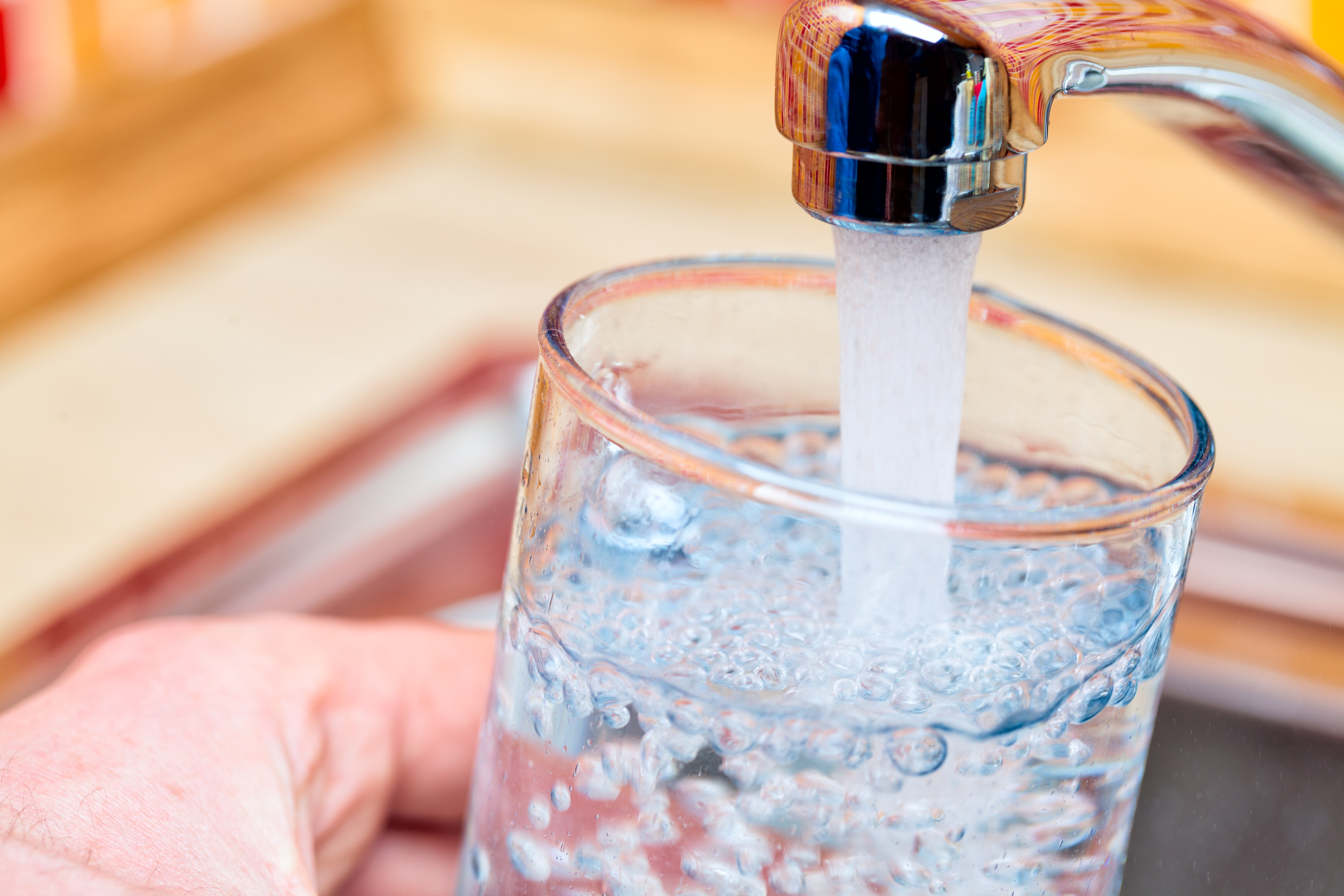 Point of view shot of a man pouring a glass of fresh water from a kitchen faucet.