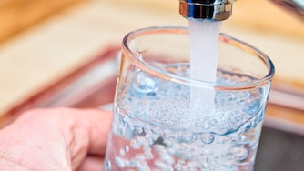 Point of view shot of a man pouring a glass of fresh water from a kitchen faucet.