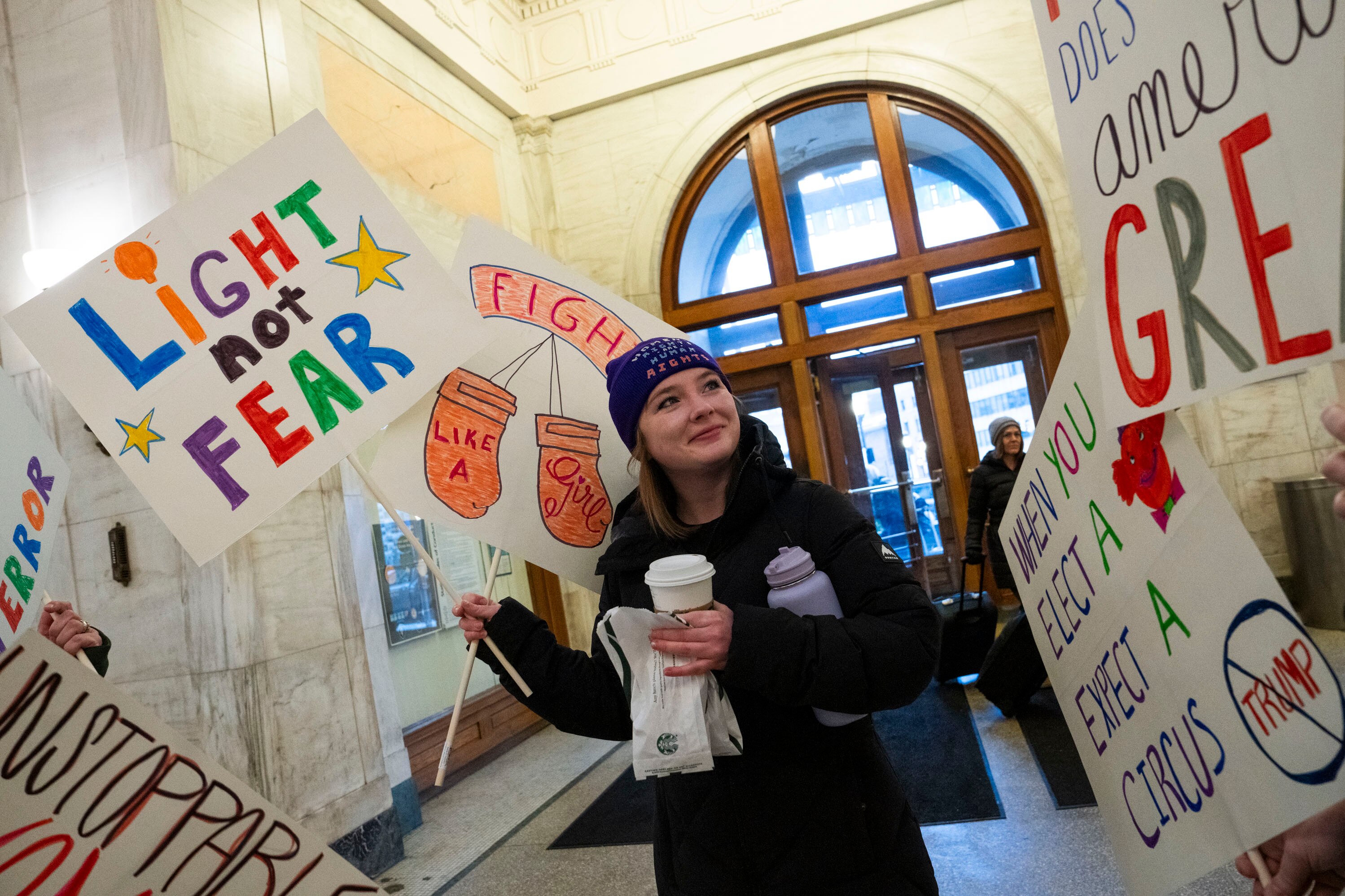 Molly Power, 26, holding protest signs, waits with family at Penn Station before hopping on the MARC train to attend the People's March in Washington, D.C., on January 18, 2025.