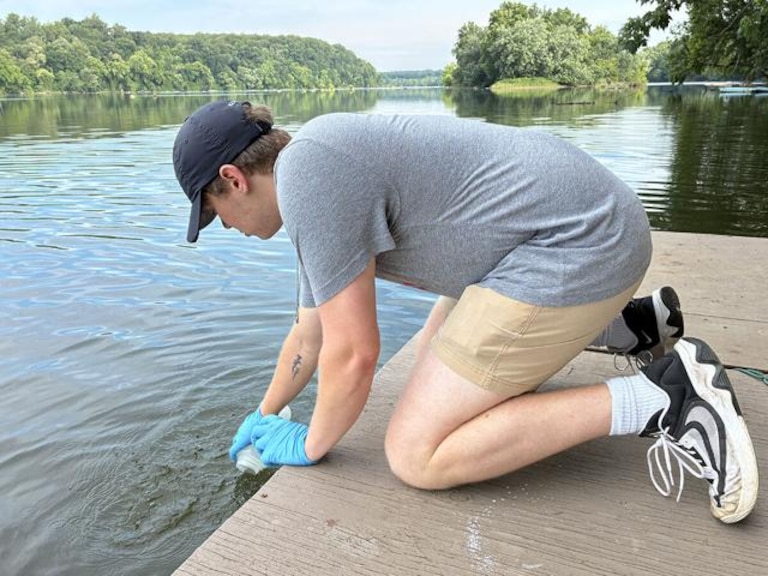 Henry Sage, a University of Maryland graduate student, collects a water sample from the Potomac River near the District of Columbia in 2026.