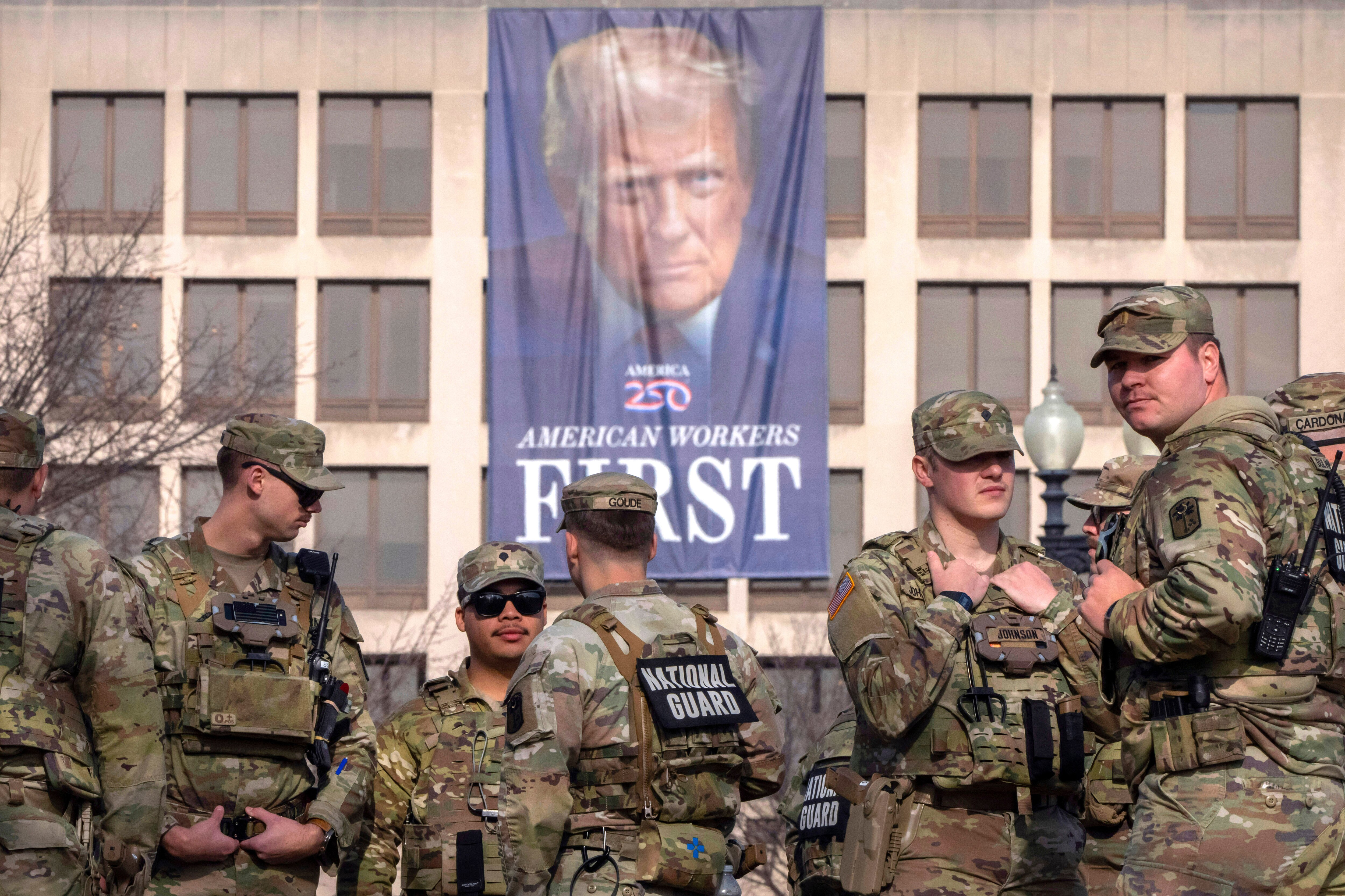 FILE - National Guard members gather near a large portrait of President Donald Trump on the Labor Department headquarters before the body of Metropolitan Police Department officer Terry Bennett is driven past the Capitol, Jan. 8, 2026, in Washington. (AP Photo/Mark Schiefelbein, File)