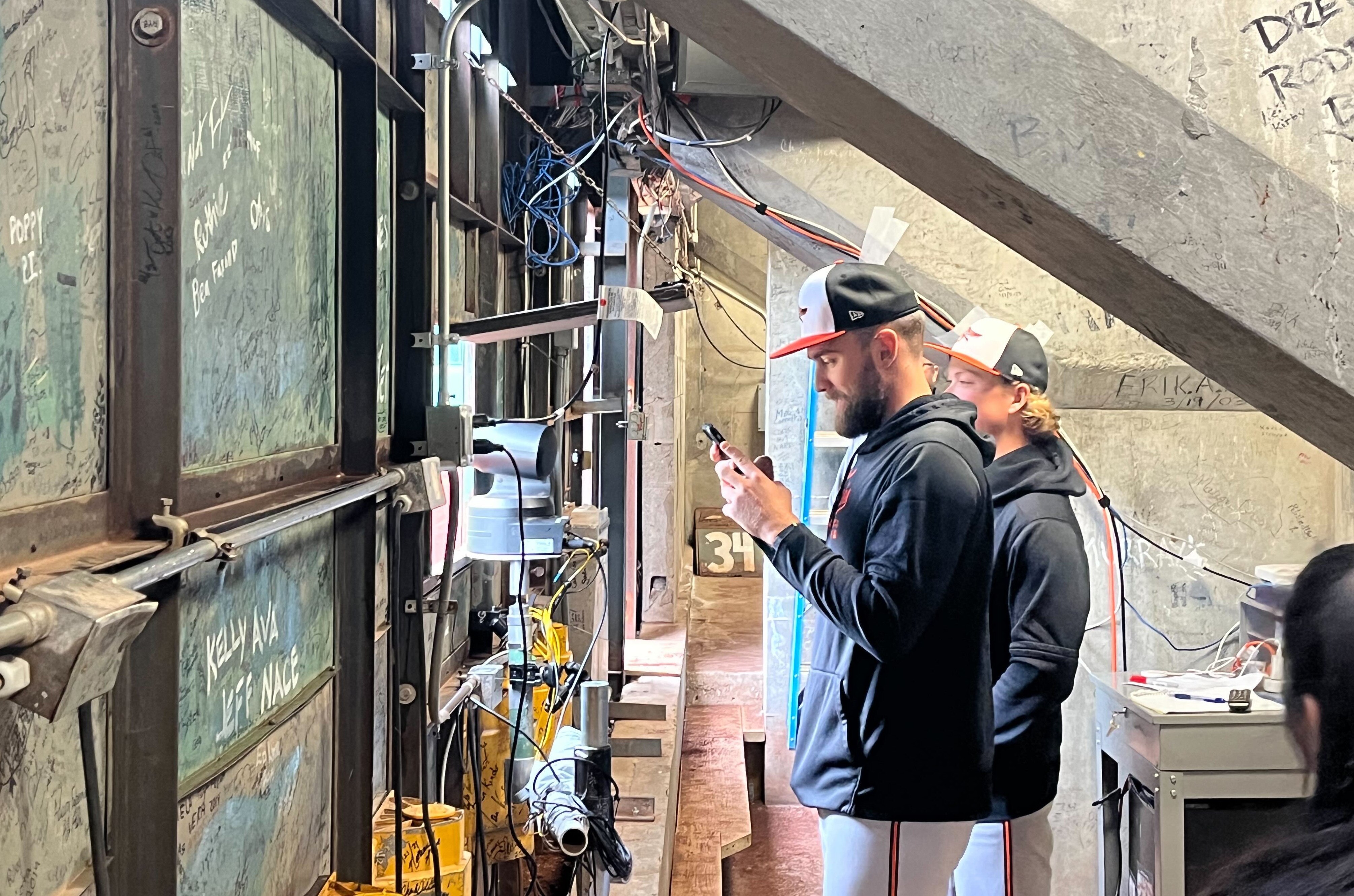 Orioles outfielder Colton Cowser, left, and second baseman Jackson Holliday stand inside the manual scoreboard in Fenway Park's Green Monster.