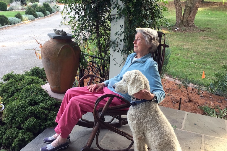 Kitty Washburne with her pet poodle on the front porch of her home in 2018.