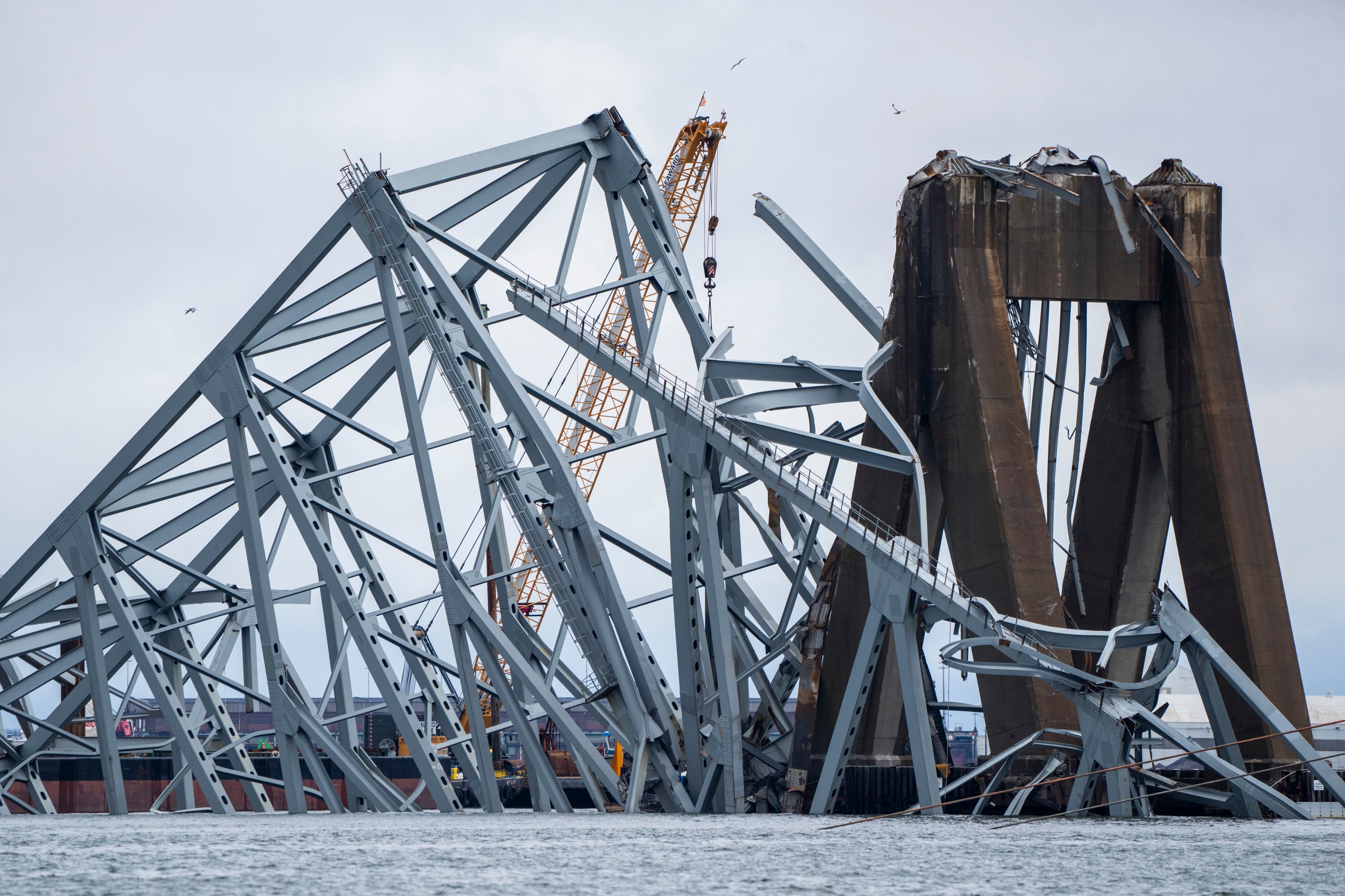 A crane helps untangle the wreckage of the Francis Scott Key Bridge in the Patapsco River.