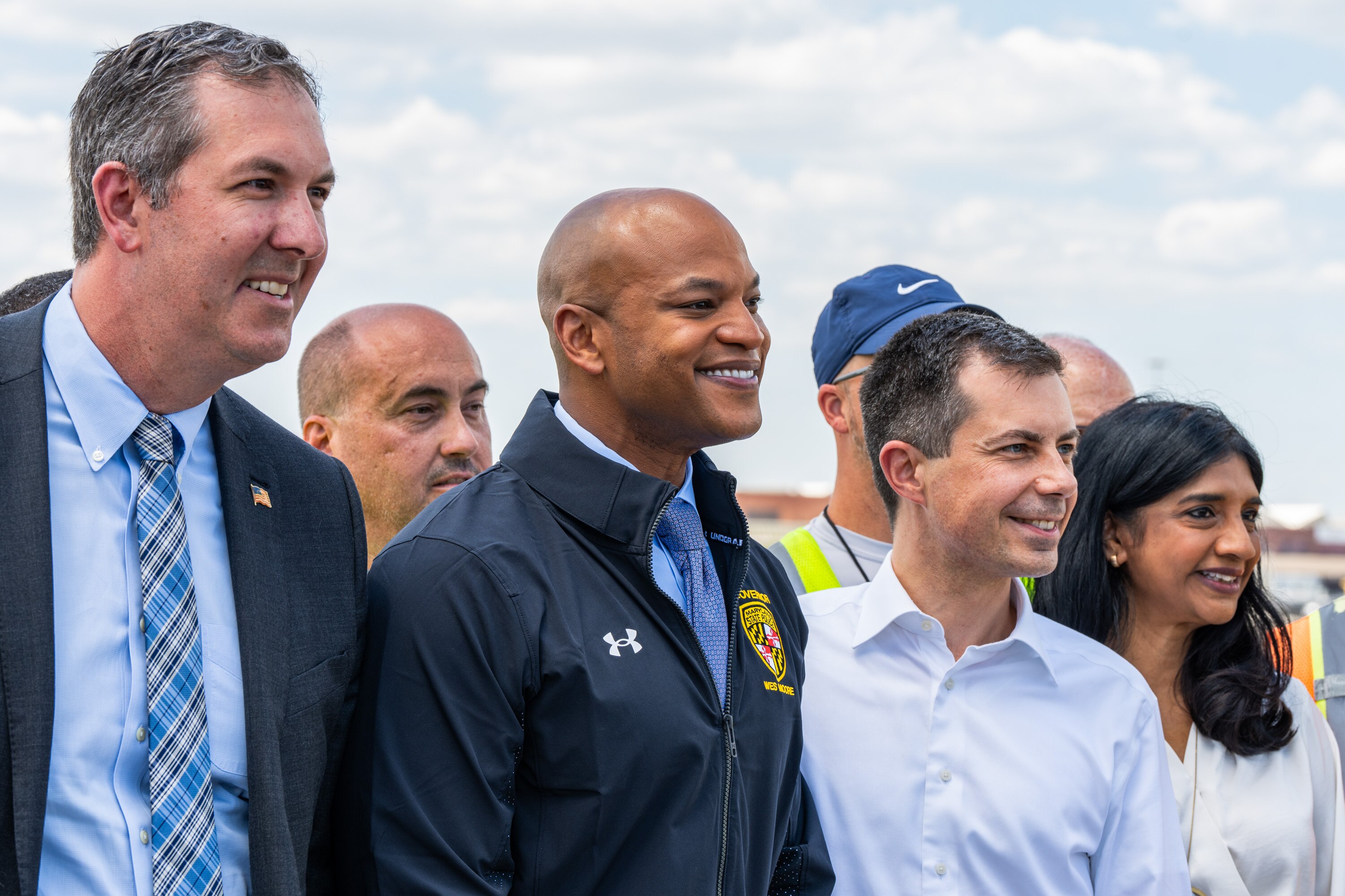 From left, Baltimore County Executive Johnny Olszewski, Gov. Wes Moore, U.S. Secretary of Transportation Pete Buttigieg and Lt. Gov. Aruna Miller smile for a group photo ahead of a press conference on the full reopening of the Fort McHenry federal channel and the restoration of full services to the Port of Baltimore in Dundalk on June 12, 2024.