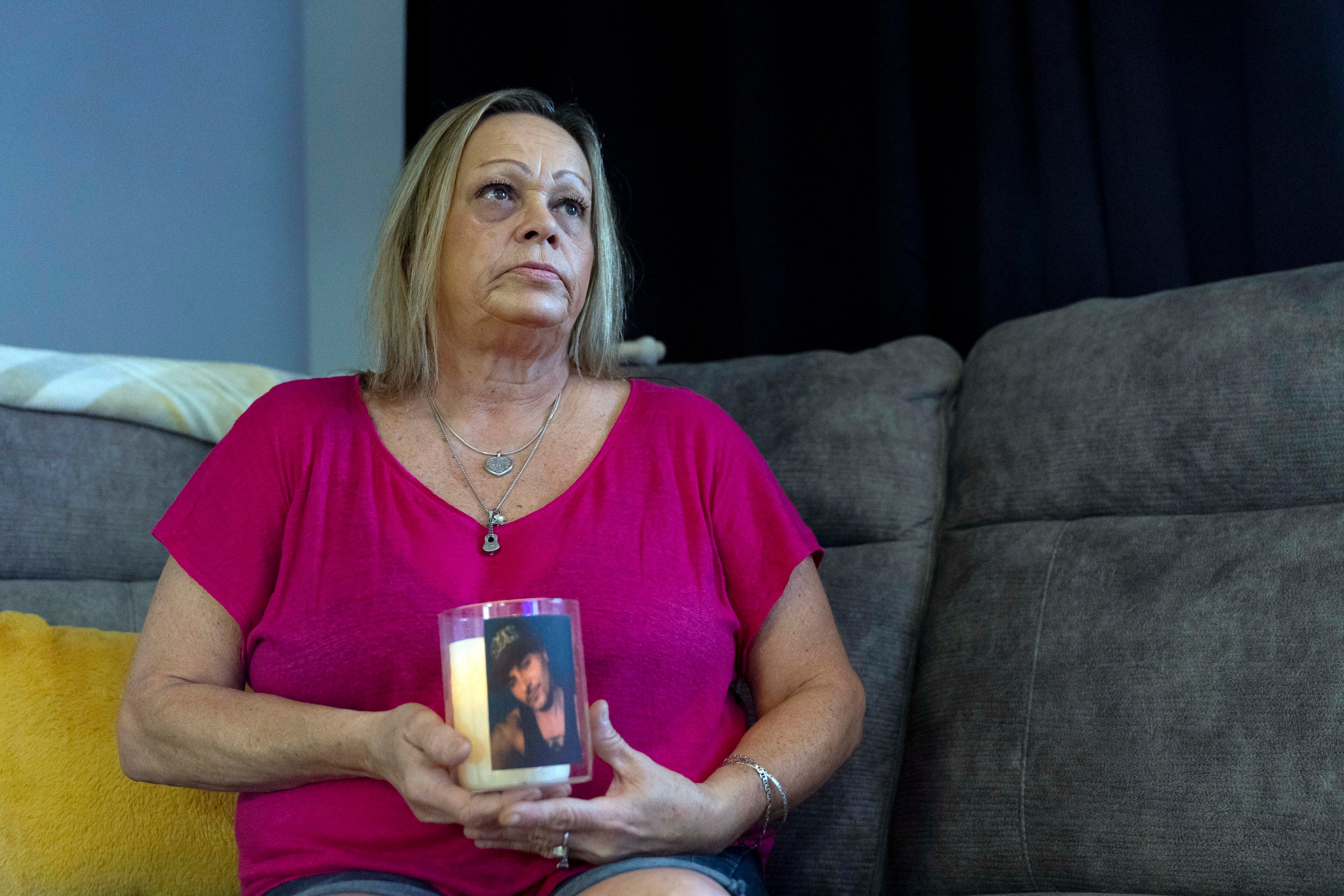 Lori Ellinger holds a candle with a photo of her son, Trea Ellinger, in her home in Glen Burnie, Maryland.