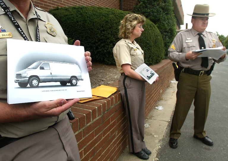 Montgomery County Police wait to hand out composites of a late model Ford and Chevy vans during a news briefing at the Montgomery County Police Headquarters October 15, 2002 in Rockville