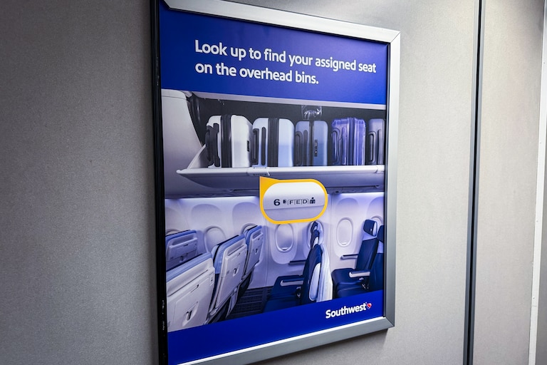 A sign in the jet bridge reminding passengers how to find an assigned seat.