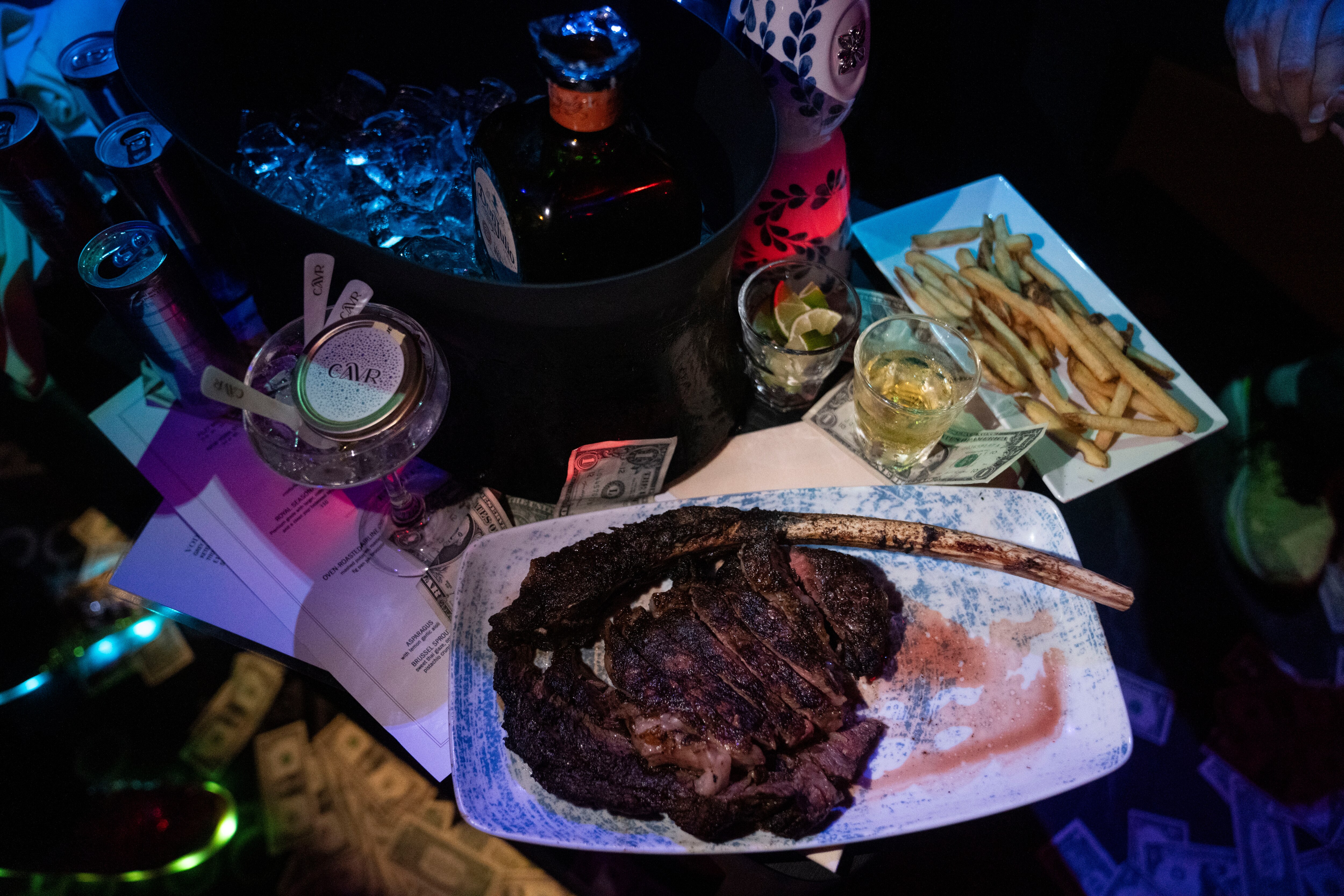 A tomahawk steak and other food and drinks on a table of a guest at The Penthouse Club in Baltimore.