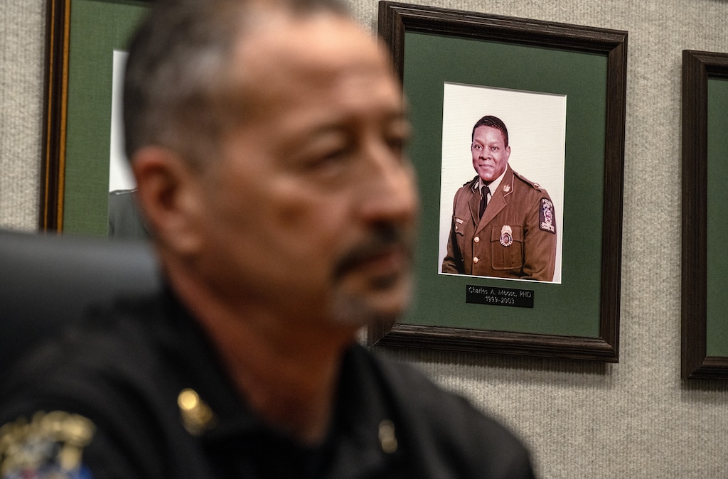 Montgomery County Police Chief Marc Yamada sits in front of portrait of former Police Chief Charles Moose