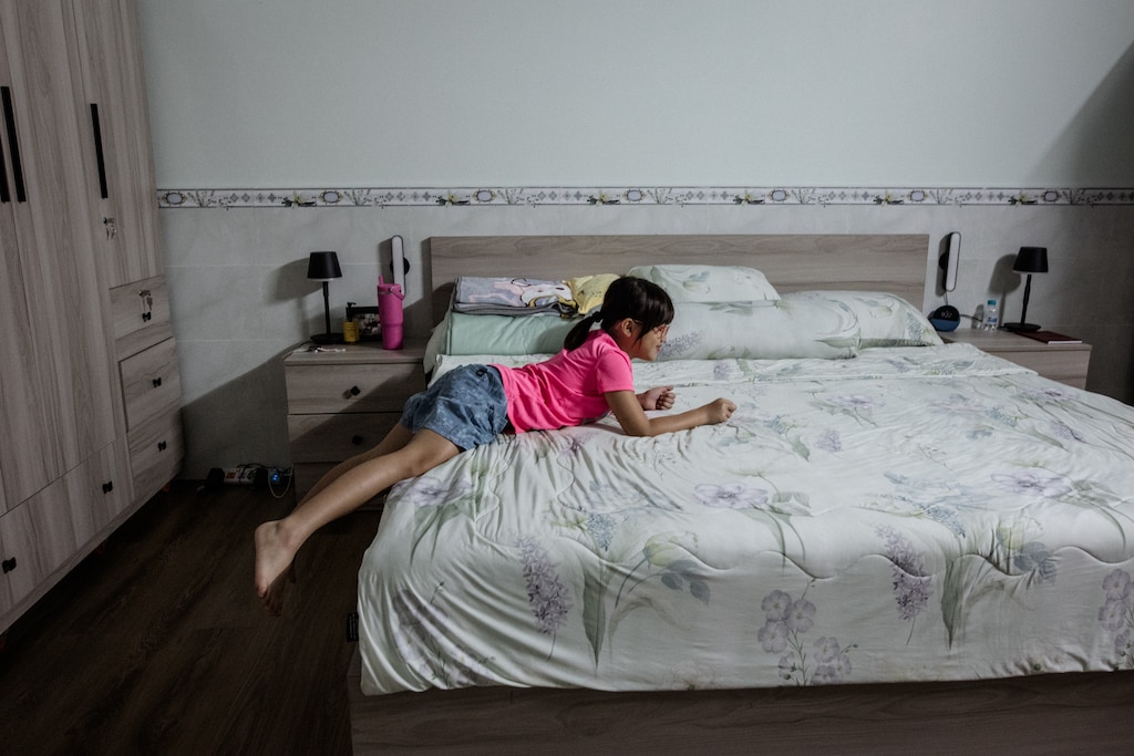 Dong Nai, Vietnam - Aug 1, 2026: Riley Hoang, 8, sprawls across her mother’s bedroom in Dong Nai, Vietnam on August 1, 2026. Rosem Morton for The Baltimore Banner