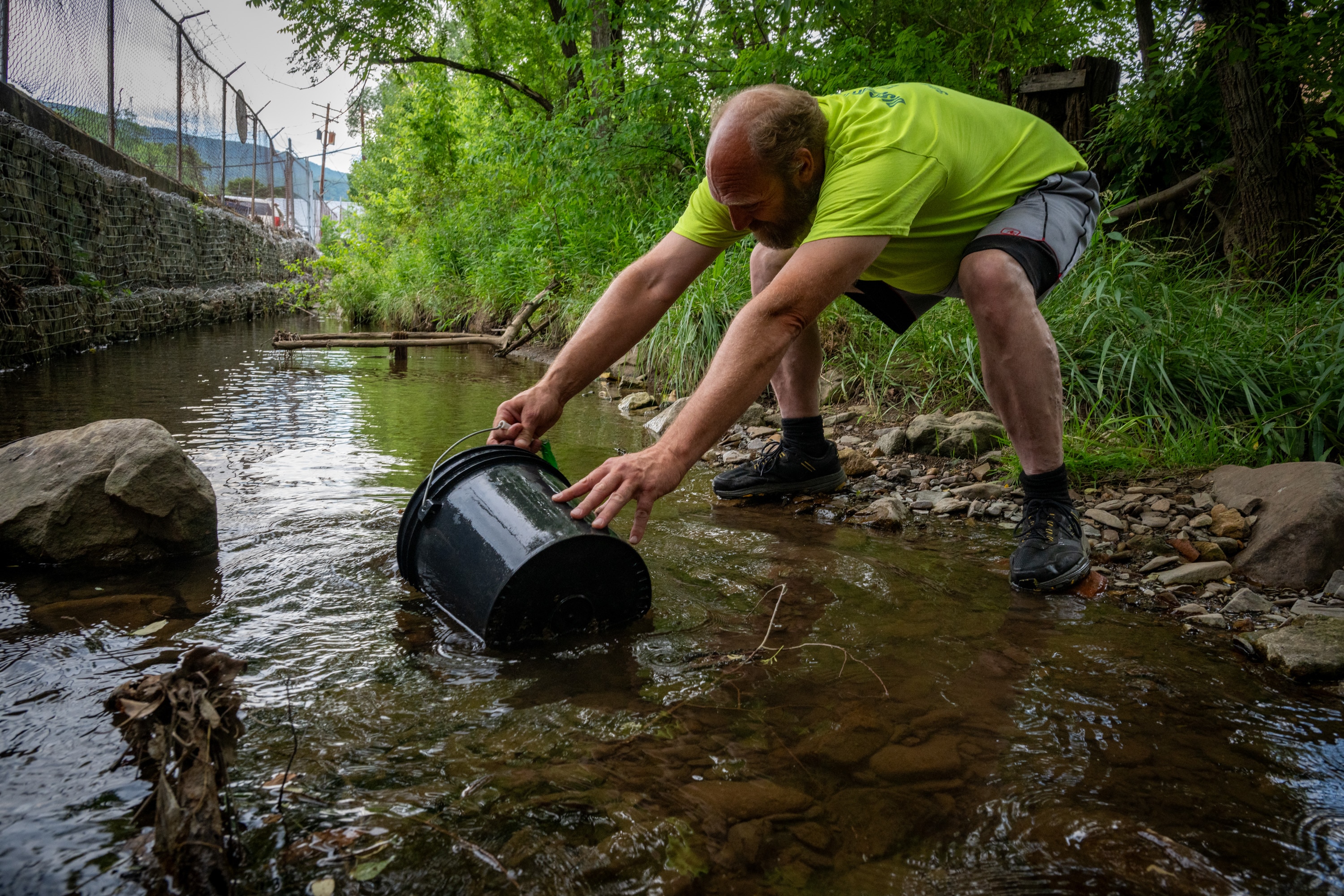 Shawn Fincham fills buckets with water from the creek behind his family’s apartment to water his plants and flush the toilet. 
