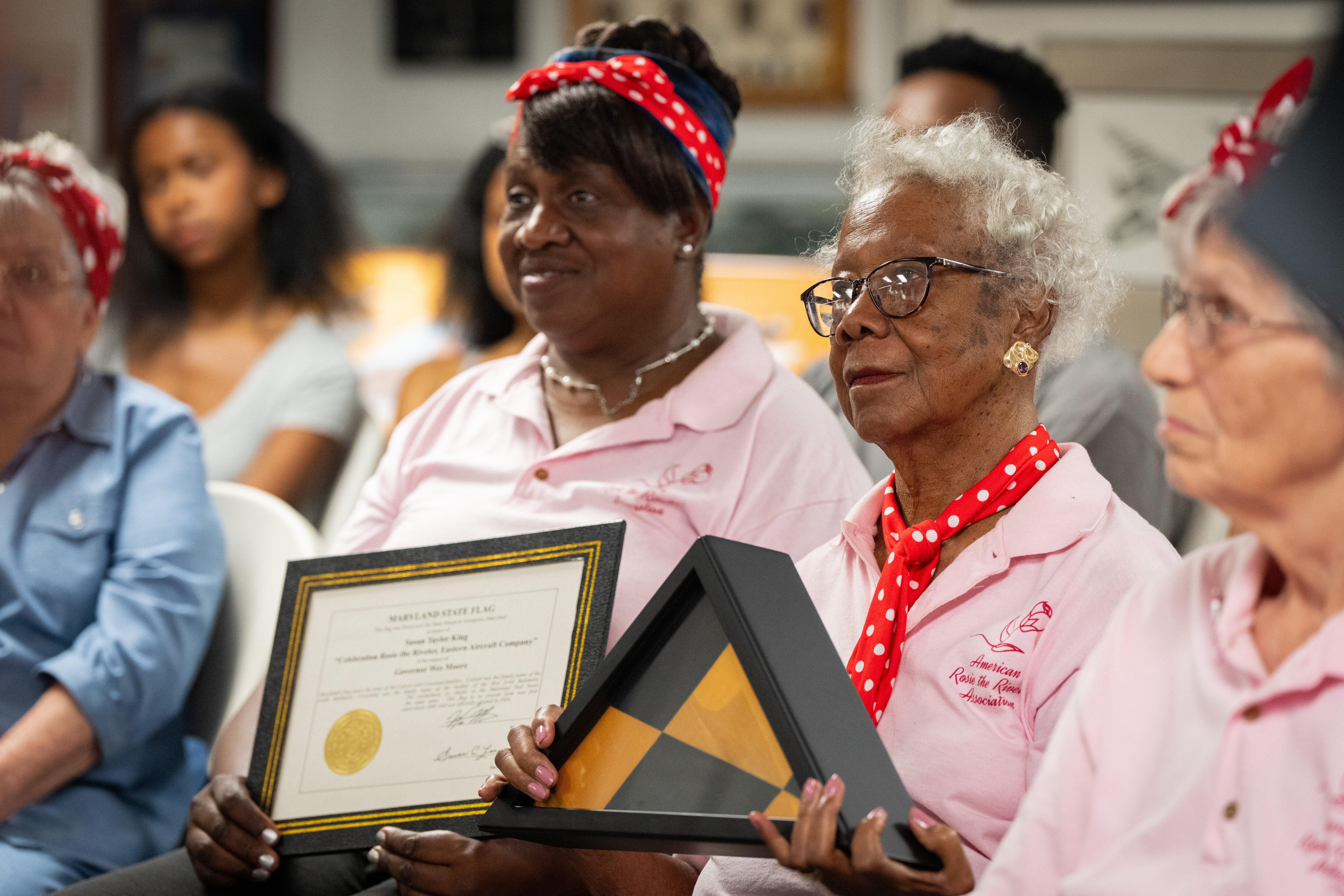 Susan King holds the triangle-folded Maryland state flag she was just honored with. Her daughter, Camille Hinmon, sits frame left holding the certificate King was also given.