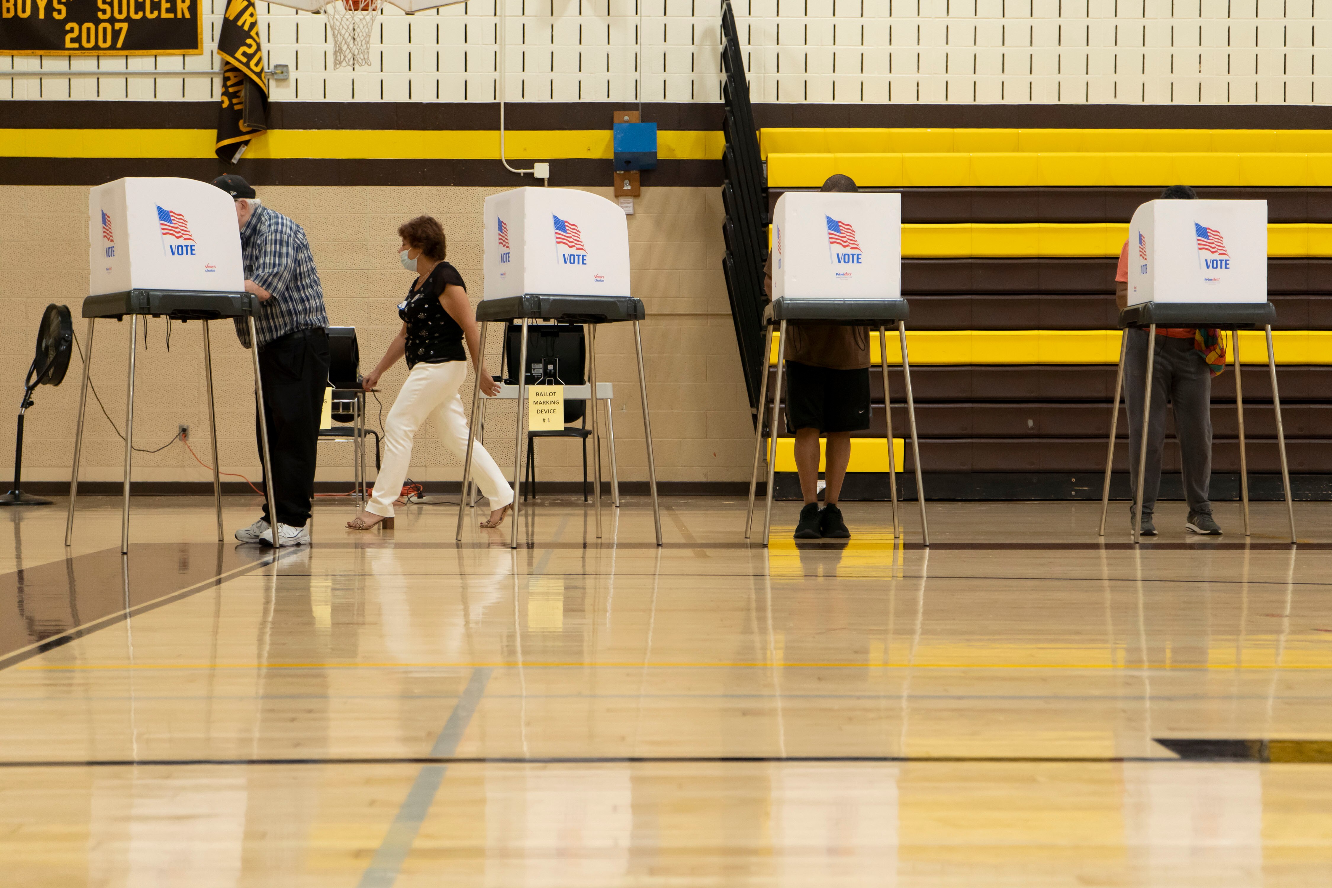 An election judge shows a voter to her voting booth at Owings Mills High School in Baltimore County.