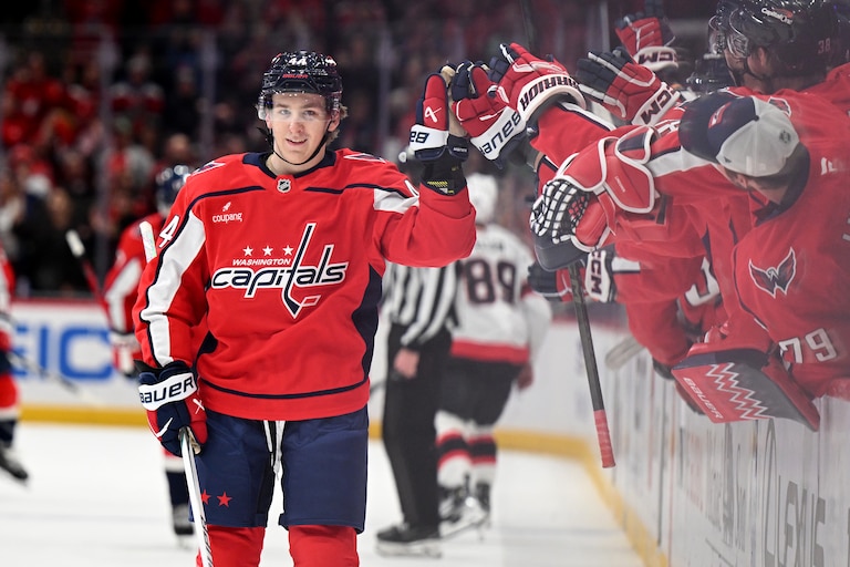 Cole Hutson #44 of the Washington Capitals celebrates with teammates at the bench area after scoring his first NHL goal into an empty net during the third period of his NHL debut against the Ottawa Senators at Capital One Arena on March 18, 2026 in Washington, D.C.
