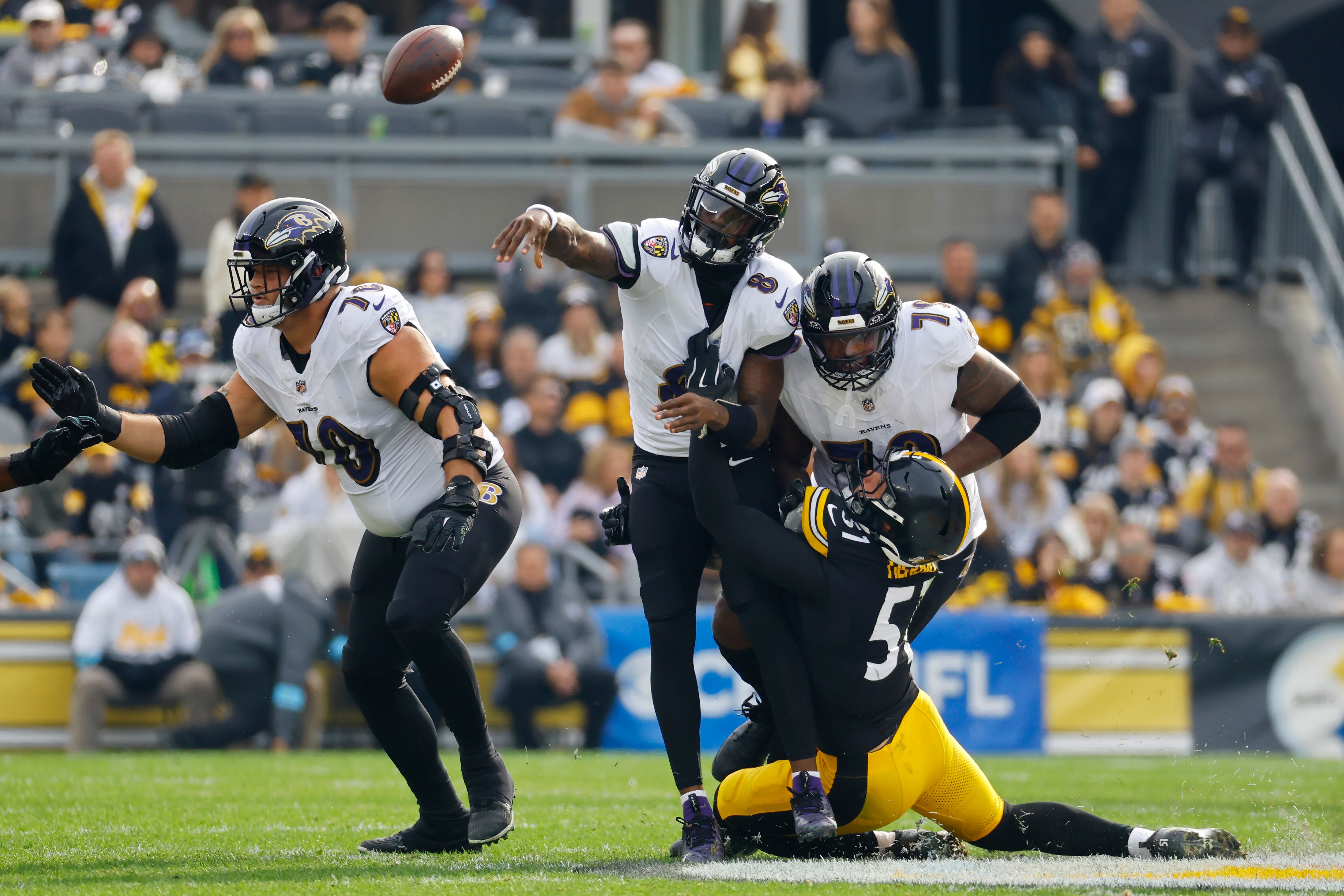 Lamar Jackson throws a wobbly pass as he is hit by Nick Herbig of the Steelers during the second quarter.