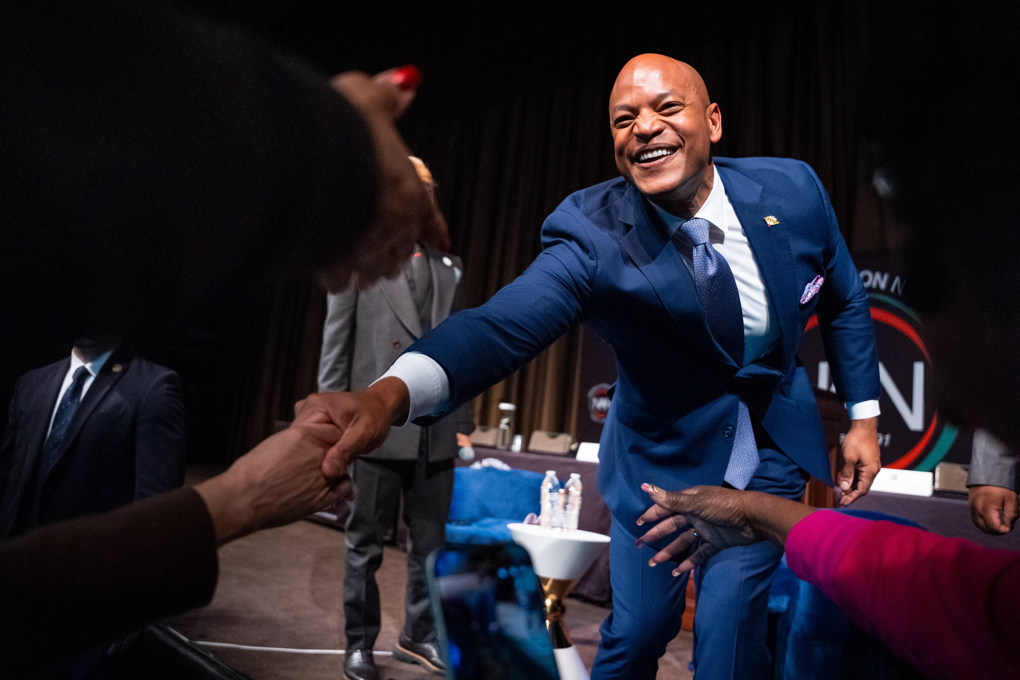 Wes Moore on stage, reaching out to shake hands with people on the floor.