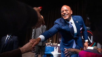 Wes Moore on stage, reaching out to shake hands with people on the floor.