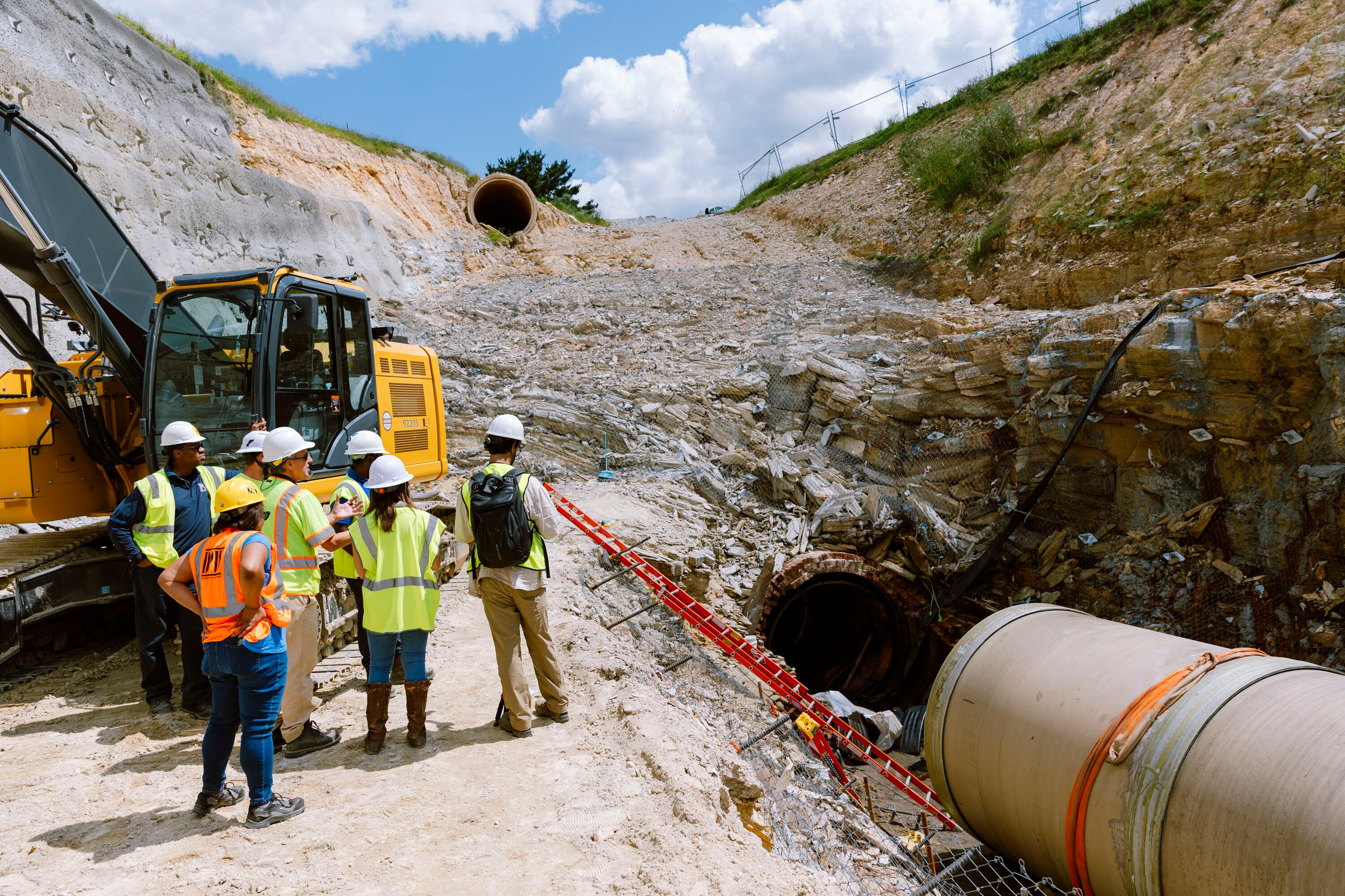 The new steel and cement replacement pipe can be seen next to a group of representatives from DPW, Garney Construction and The Baltimore Banner at the bottom of a six-story deep excavation at Lake Montebello on Thursday, Aug. 22, 2024 in Baltimore, MD.