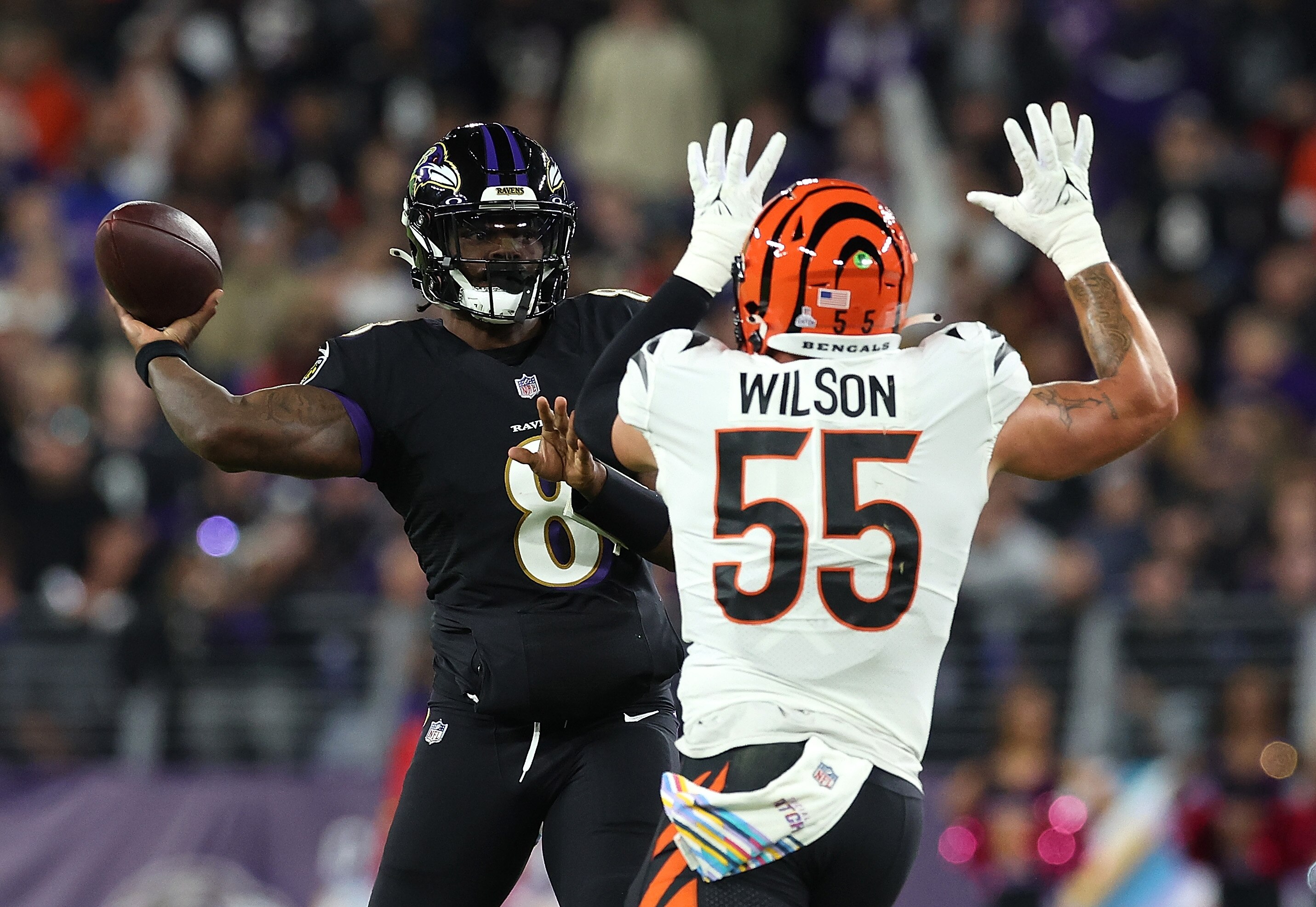 BALTIMORE, MARYLAND - OCTOBER 09:  Lamar Jackson #8 of the Baltimore Ravens looks to pass as he is pressured by Logan Wilson #55 of the Cincinnati Bengals in the first quarter at M&T Bank Stadium on October 09, 2022 in Baltimore, Maryland.