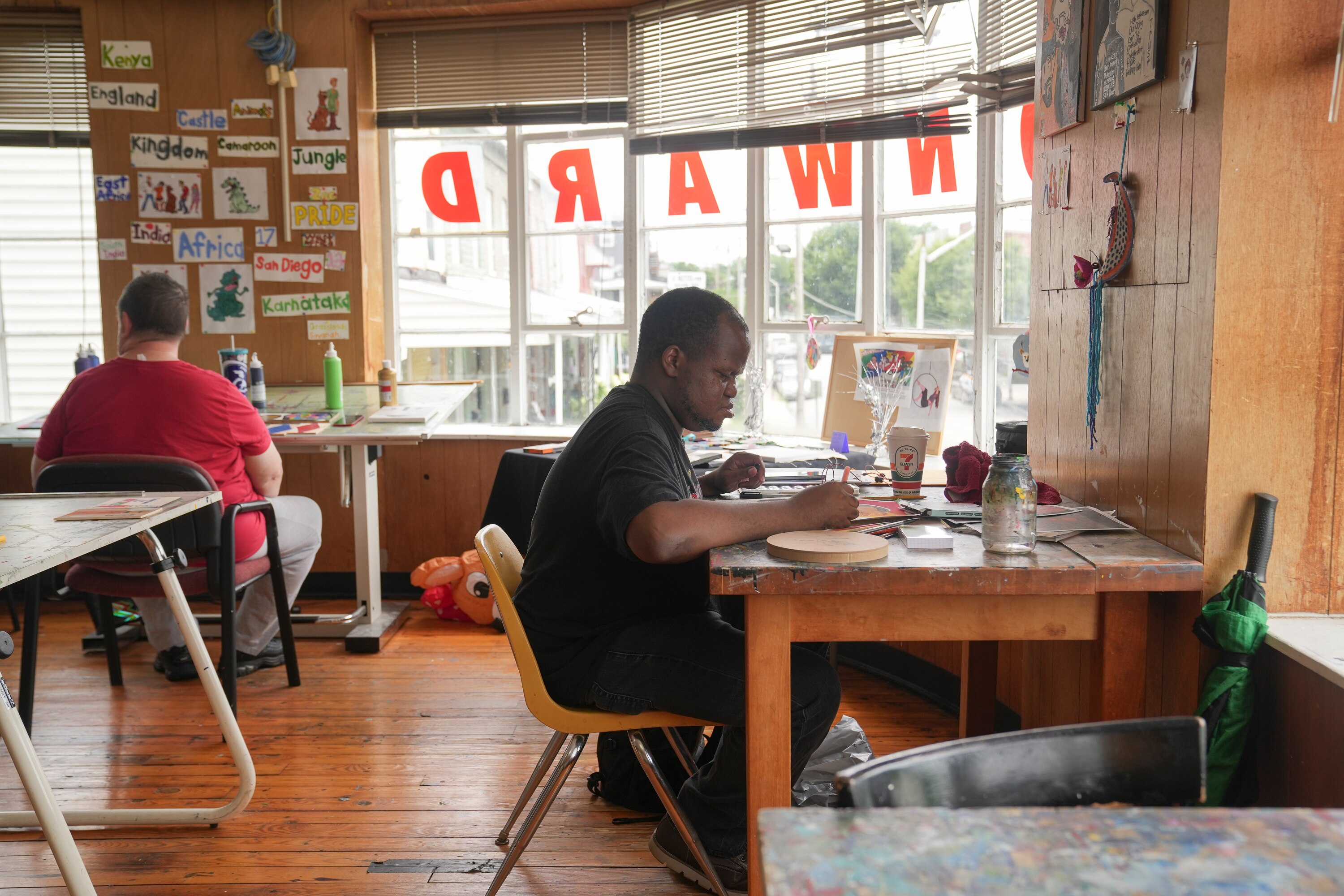 Tyrone Weedon paints at his workstation. His art hangs over his desk.