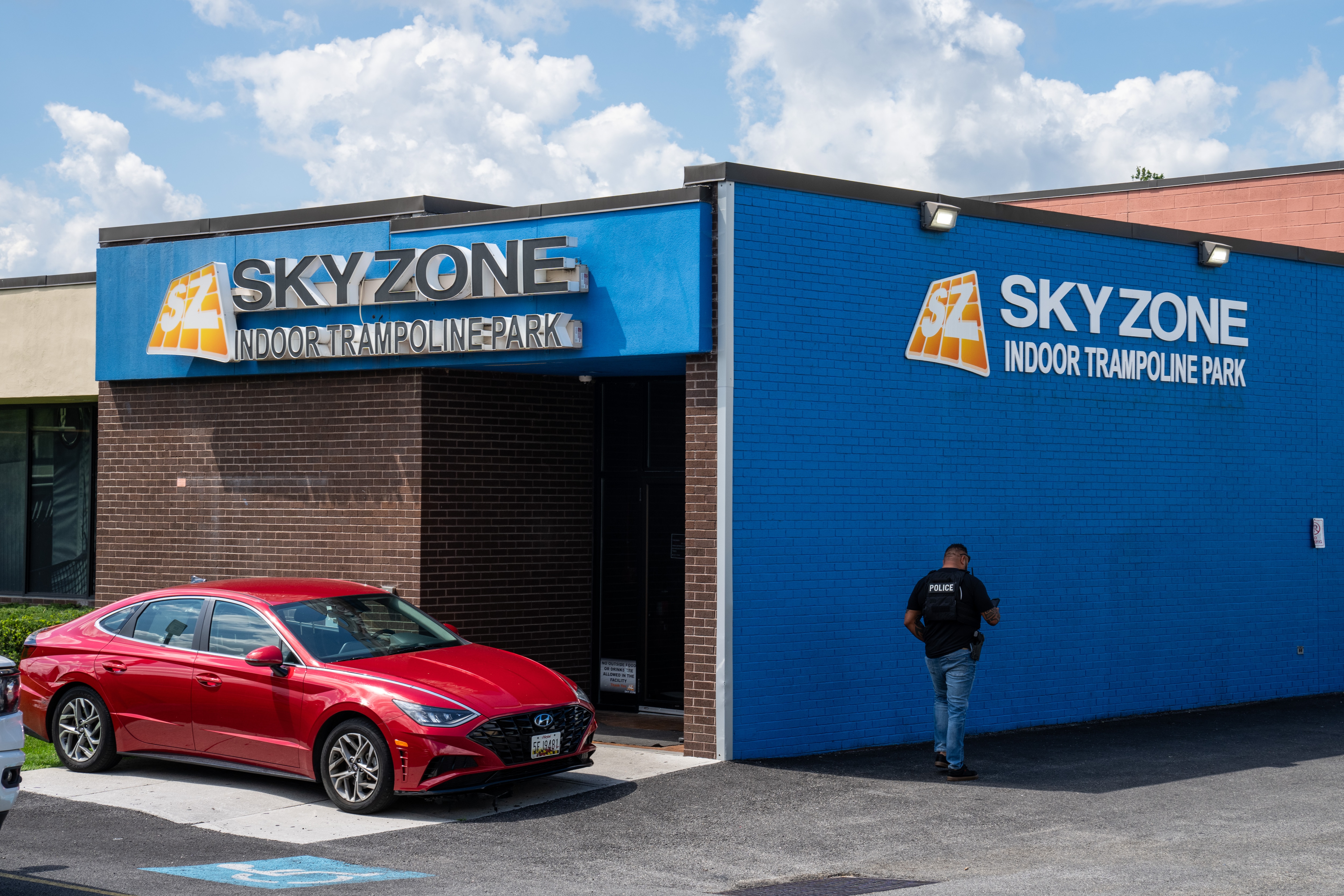 A police officer with his back to the camera walks in front of Sky Zone.