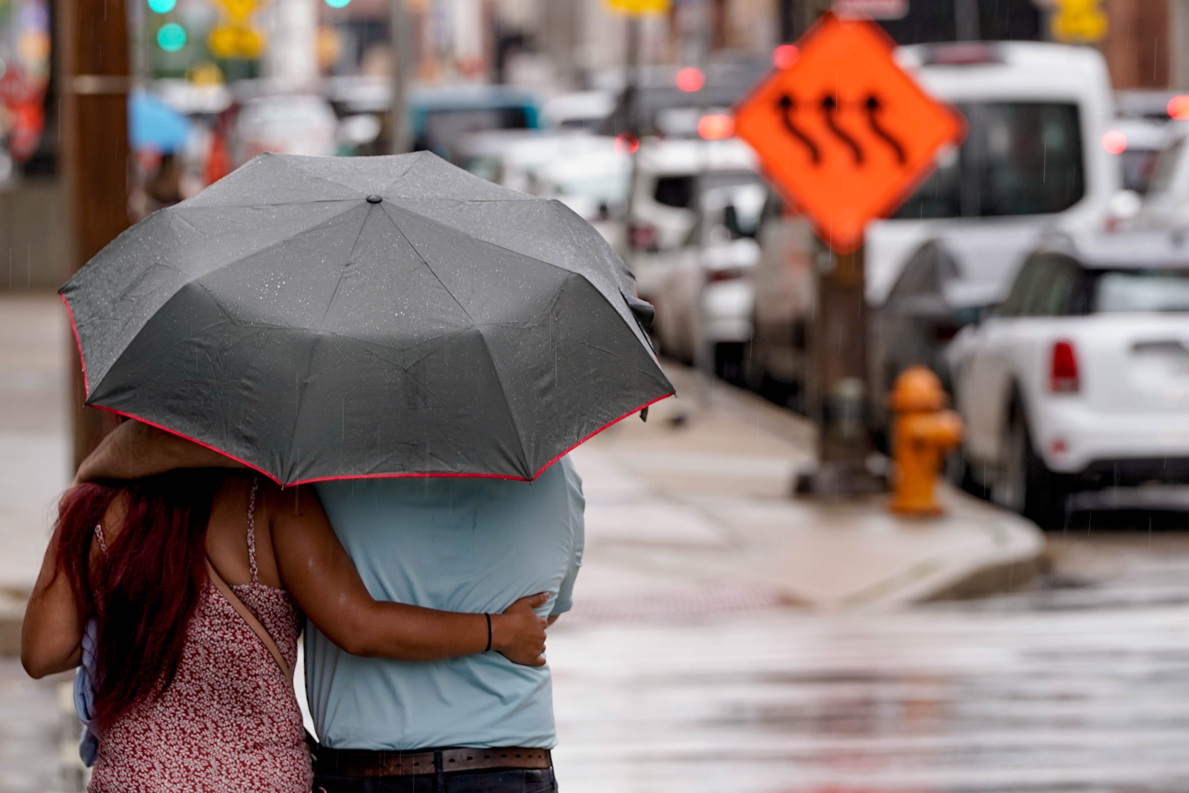 Jeff and Kim walk through the rain under one umbrella in downtown Baltimore on July 9, 2023.