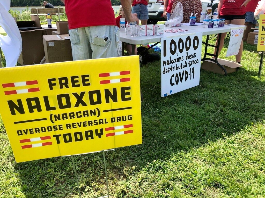 Free Naloxone signs are displayed at a tent during a health event on June 26, 2021, in Charleston, W.Va.