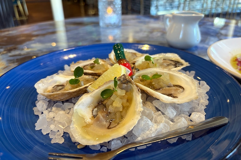 Oysters are served on the half-shell and topped with compress-pickled apple and cucumber at Nora Blú.