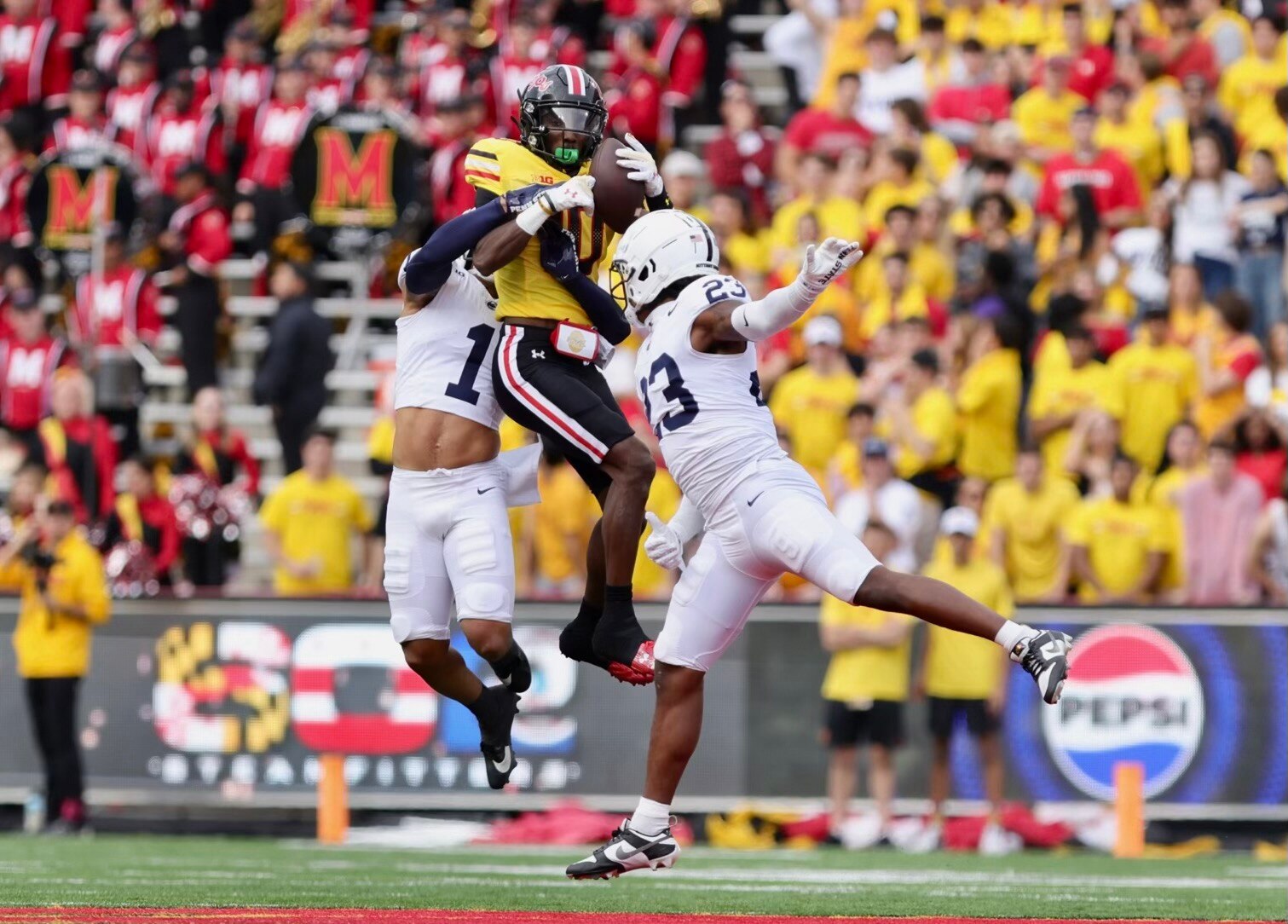 Maryland’s Tai Felton catches a pass between Penn State defenders. (Lexi Thompson/For the Baltimore Banner)