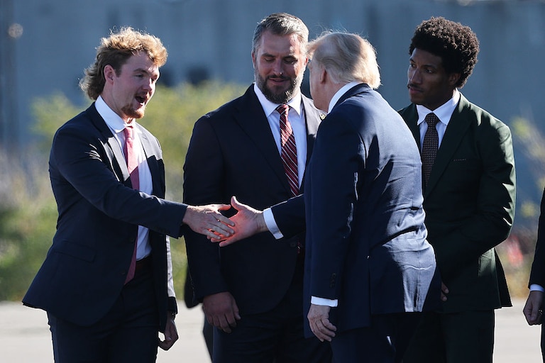 President Donald Trump greets members of the Baltimore Ravens, from left to right, punter Ryan Eckley, long snapper Nick Moore and cornerback Marlon Humphrey, as he arrives to speak at Tradepoint Atlantic.