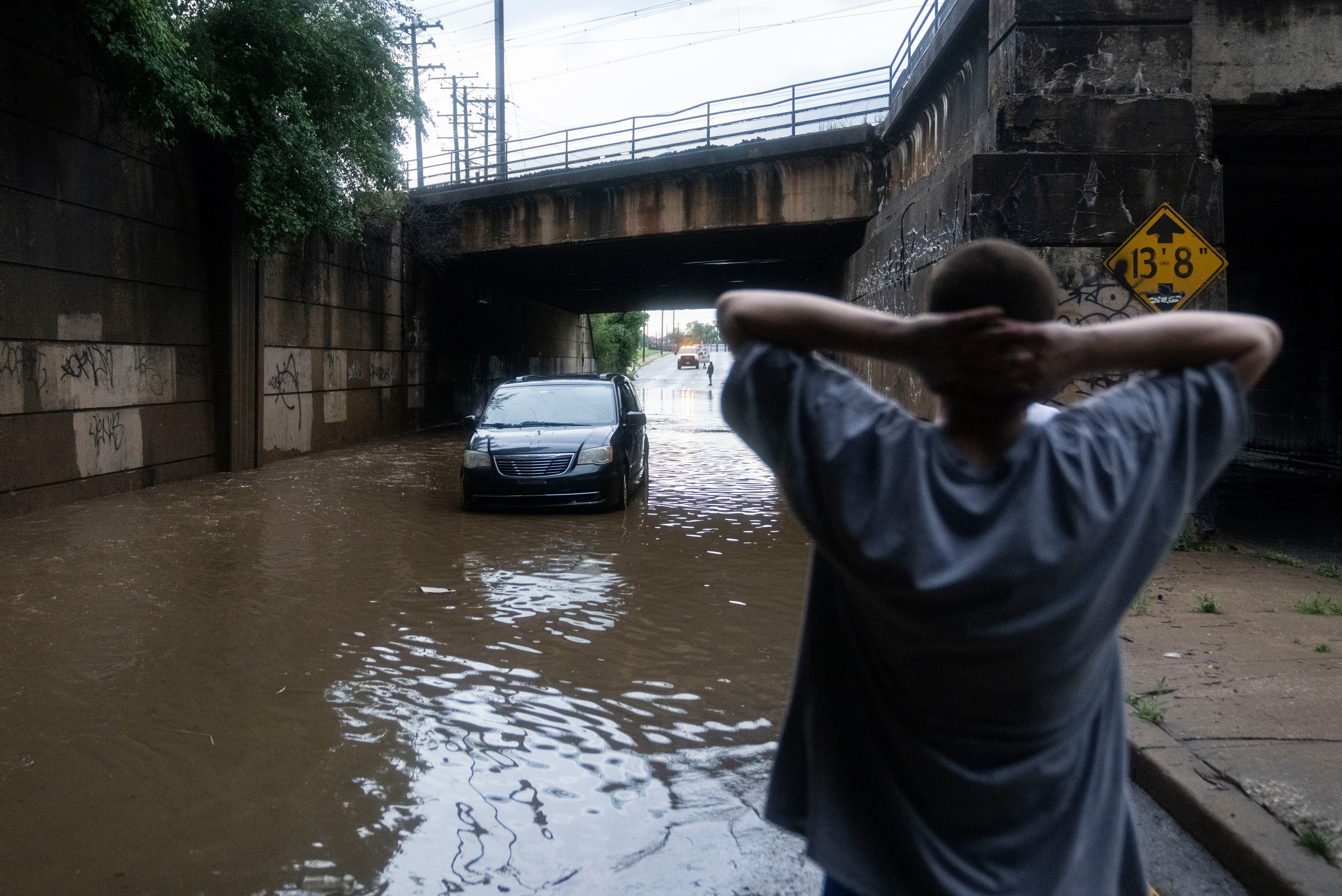 Joshua Jennings Jr. looks at his vehicle that’s trapped under an overpass after a fast-moving thunderstorm on North Point Road, in Baltimore, Tuesday, July 1, 2025.