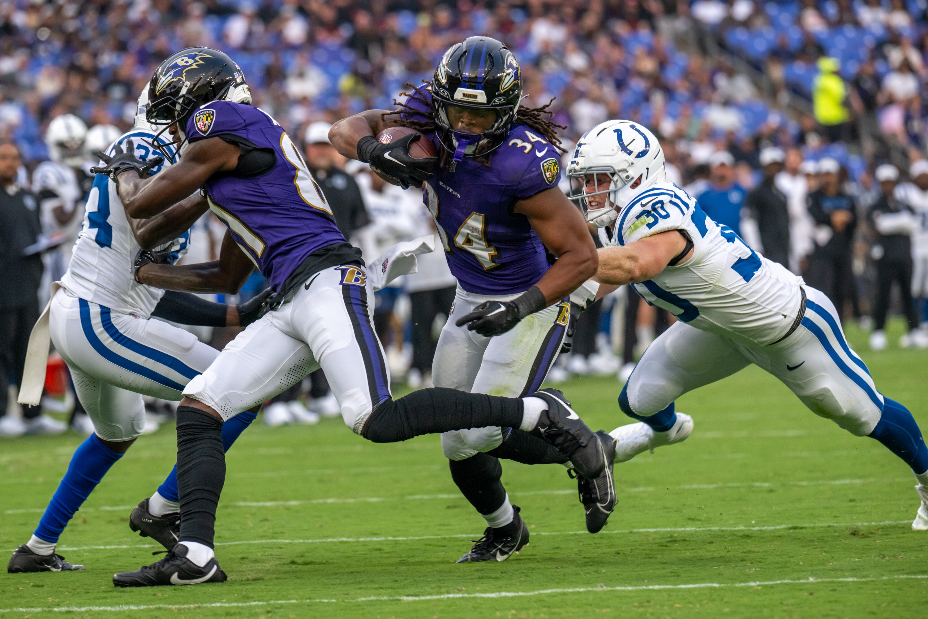 Baltimore Ravens running back Keaton Mitchell (34) eludes several Indianapolis Colts defenders in the first quarter at M&T Bank Stadium.