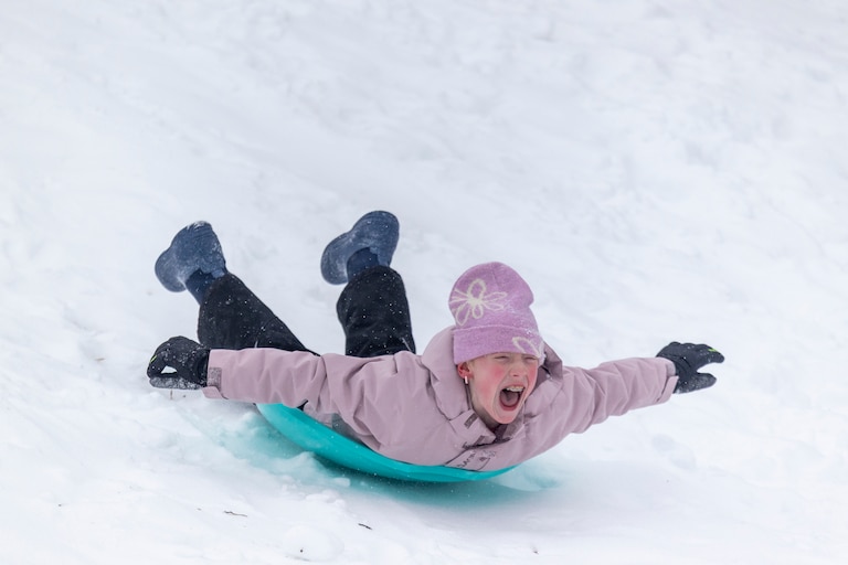 A girl sleds down a hill on Sunday, Jan. 25, 2026, during a snowstorm in Silver Spring, Md. at Pinecrest Park.