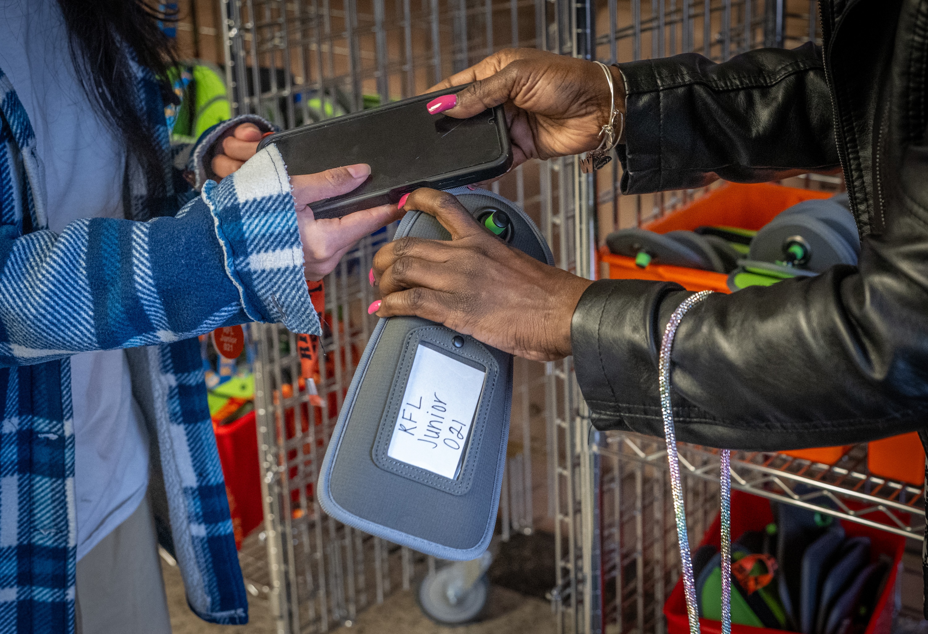 Principal Shawnette Williams collects a cellphone from a student arriving at Reginald Lewis High School. The phones are put in numbered pouches and locked up until the end of the school day.
