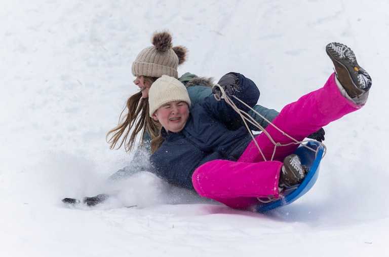 Cynthia Ferguson, left, and Joni Kayne sled down a hill on Sunday, Jan. 25, 2026, during a snowstorm in Silver Spring, Md. at Pinecrest Park.