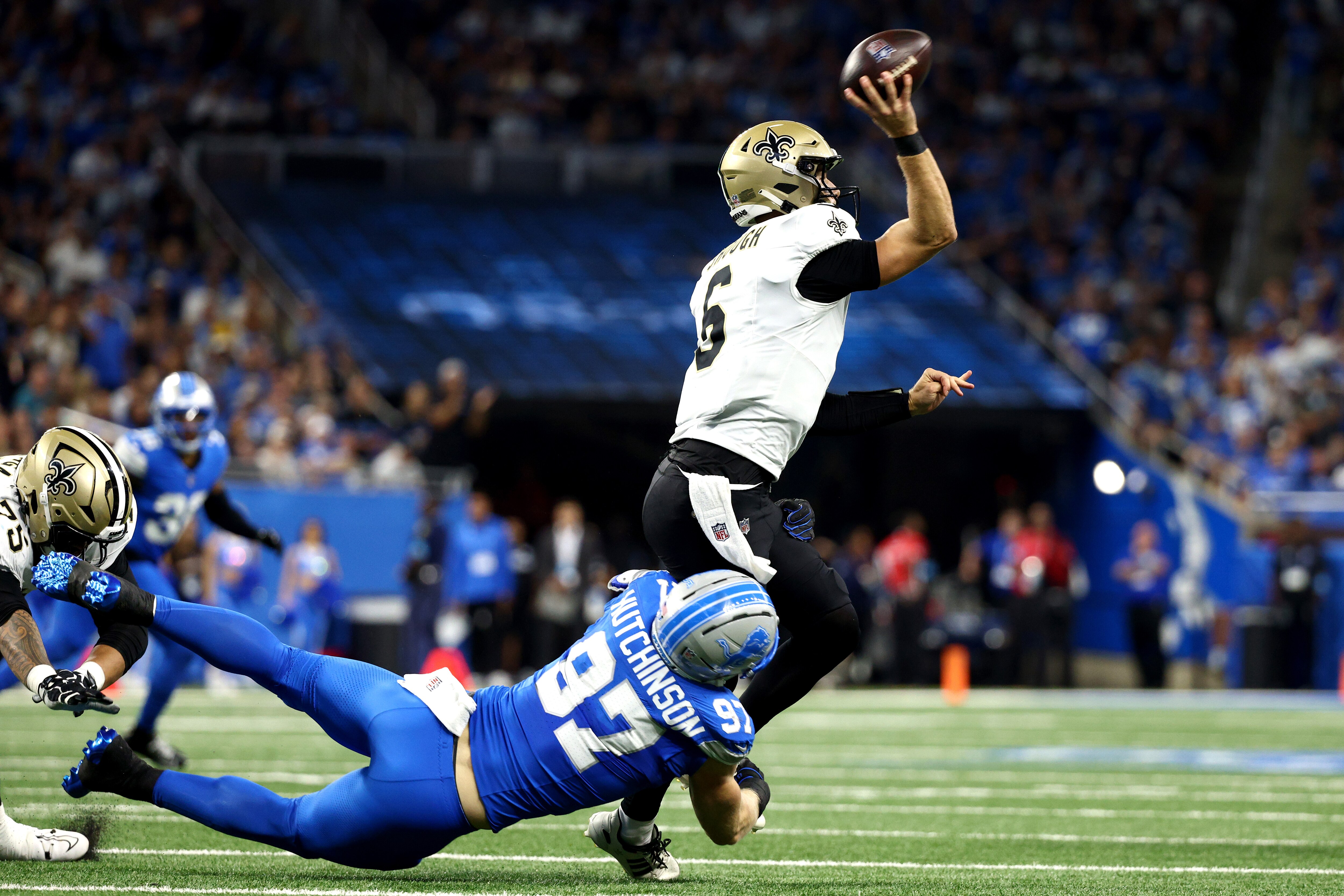 Tyler Shough of the Saints passes with Aidan Hutchinson of Detroit at his feet. The Ravens would do well to replicate that pressure on Shough.
