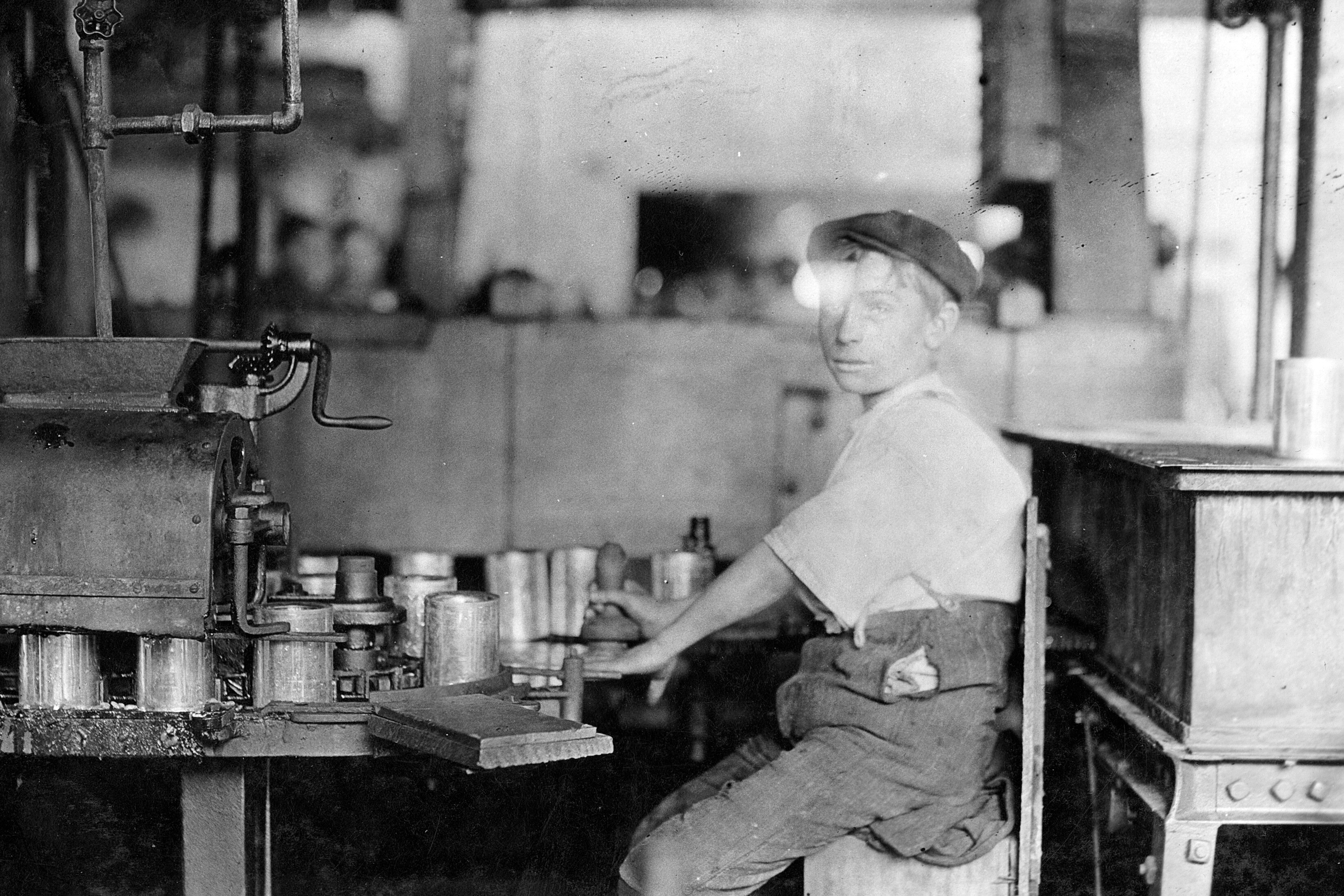 Lewis Wickes Hine, Dangerous Business. Boy working at canning machine with open gearing. Many such machines and boys too. J. S. Farrand Packing Co., Baltimore, Maryland, 1909. Gelatin silver print, 5 x 7 in. The Photography Collections, University of Maryland, Baltimore County (UMBC), P858
