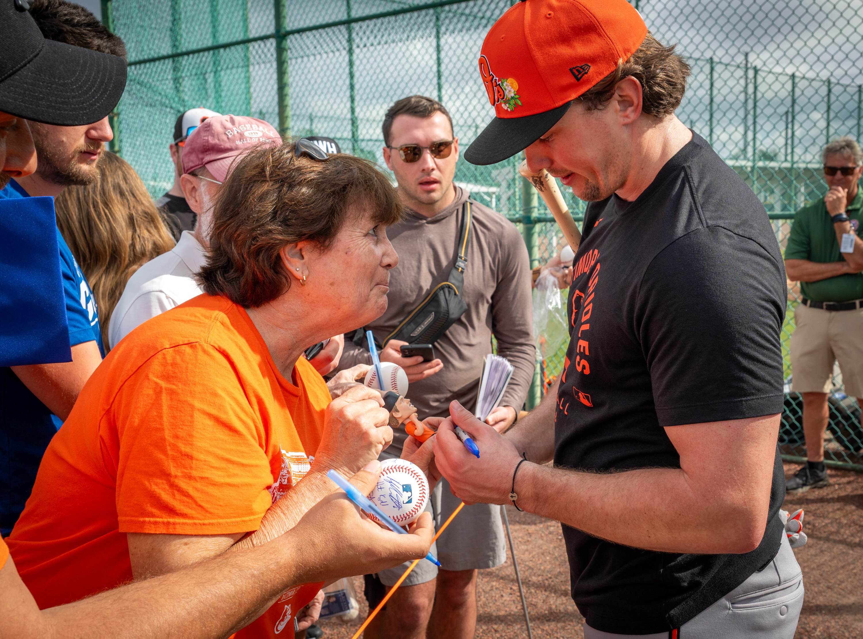 Terri Hett, left, of Perry Hall, gets her bobblehead signed by the Orioles’ Adley Rutschman on the second day of spring training at Ed Smith Stadium in Sarasota, Fla.