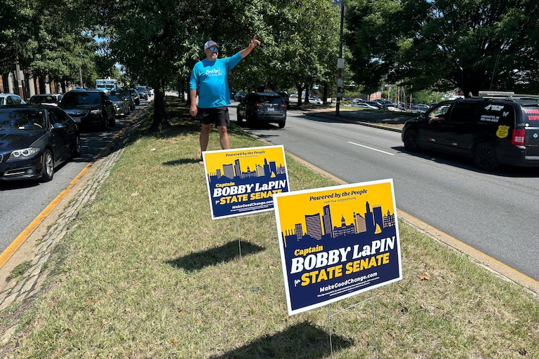 Drivers honk and wave to Bobby LaPin as he plants his campaign signs on a median strip of Boston Street one day after his primary loss.