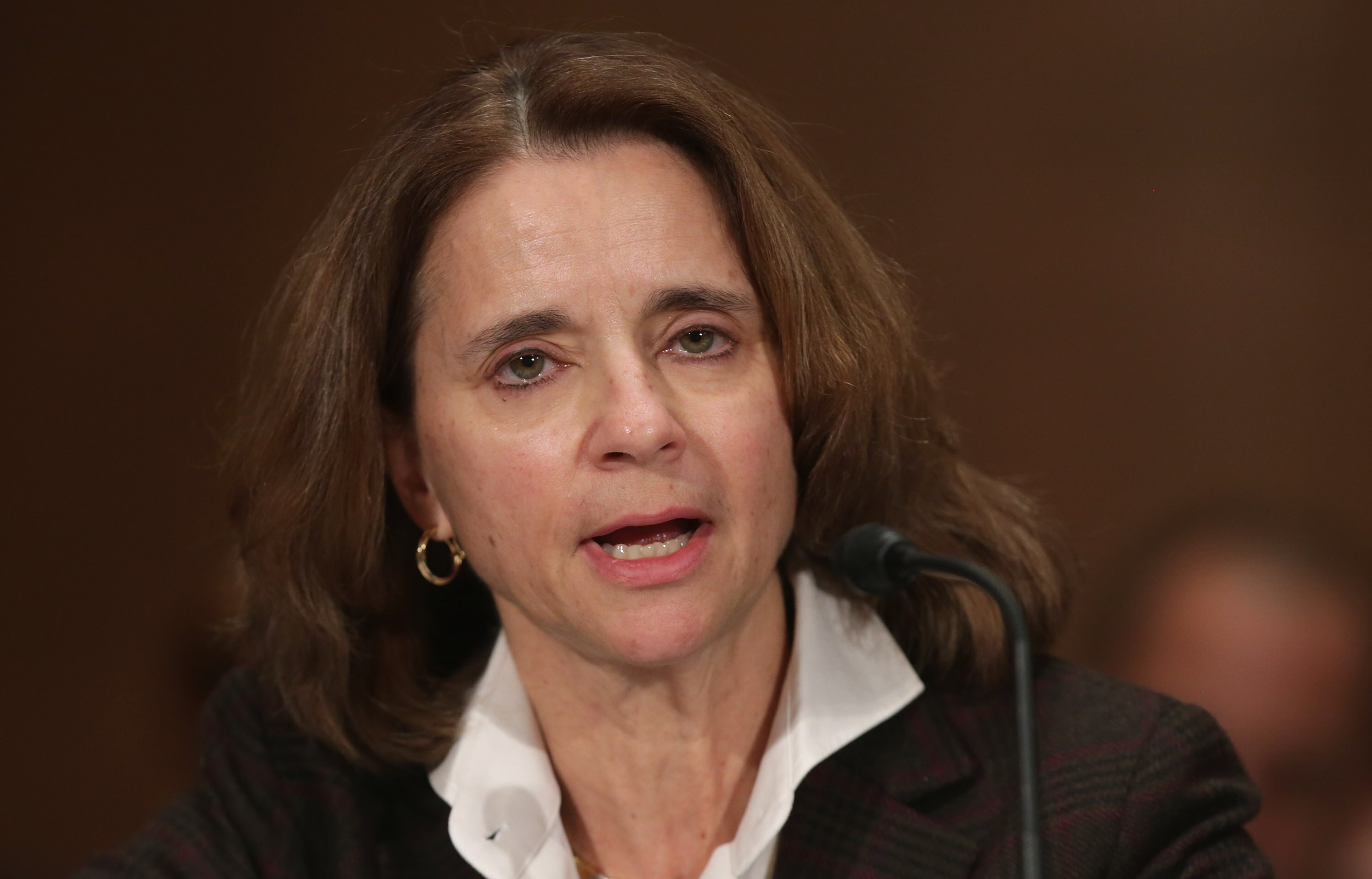 A close up of Mary Miller speaking into a microphone at a congressional hearing. She is wearing a black jacket and white shirt.