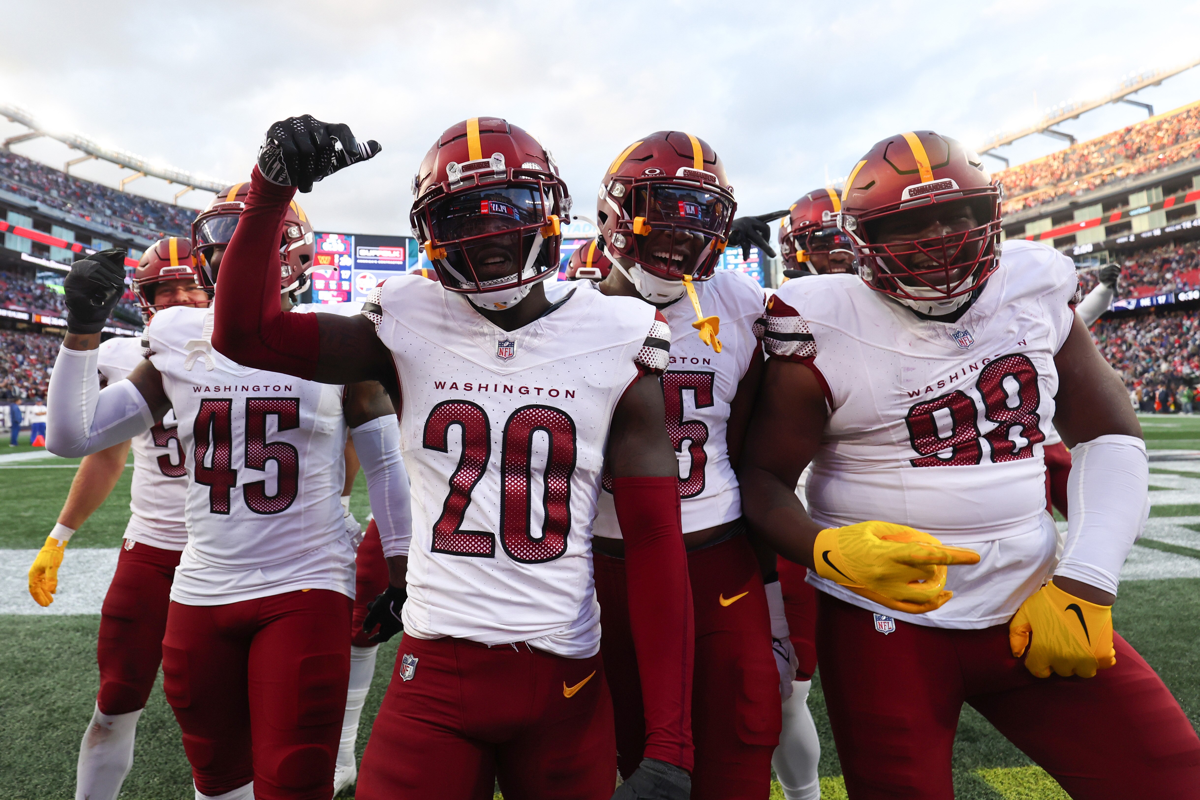 Jartavius Martin (20) and his Commanders teammates celebrate his interception against the Patriots.