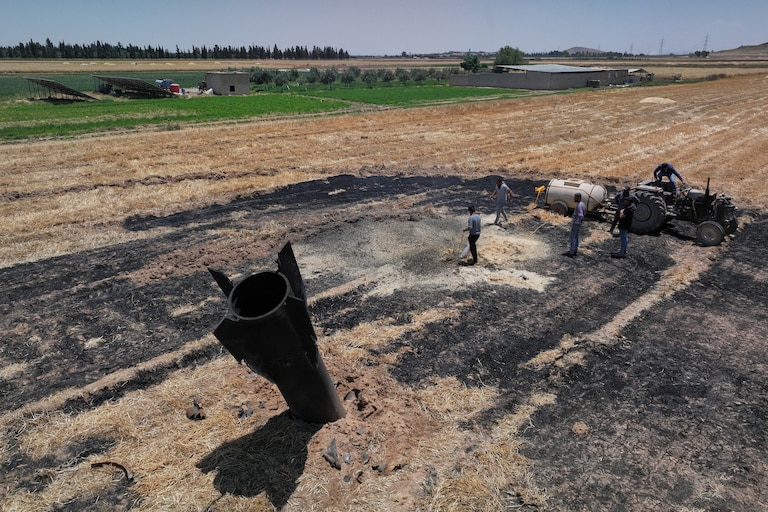 Farmers spray water in a burned agricultural field next to a projectile near the town of Najha, Syria, Monday, June 8, 2026, after debris from Iranian missile launches during the Iran-Israel conflict fell in the area.