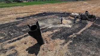 Farmers spray water in a burned agricultural field next to a projectile near the town of Najha, Syria, Monday, June 8, 2026, after debris from Iranian missile launches during the Iran-Israel conflict fell in the area.