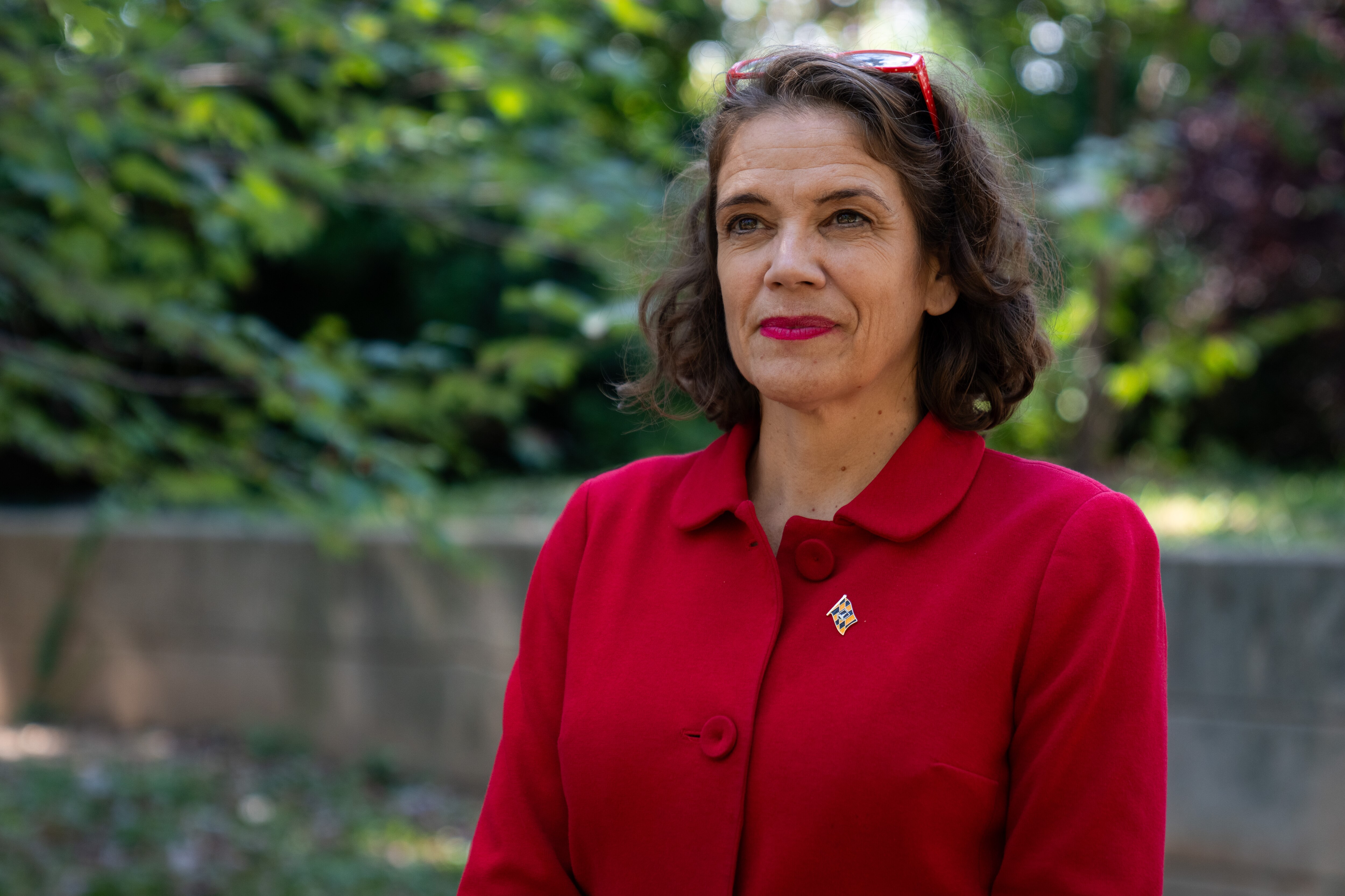 Odette Ramos looks away from the camera for a portrait in a shady green space.