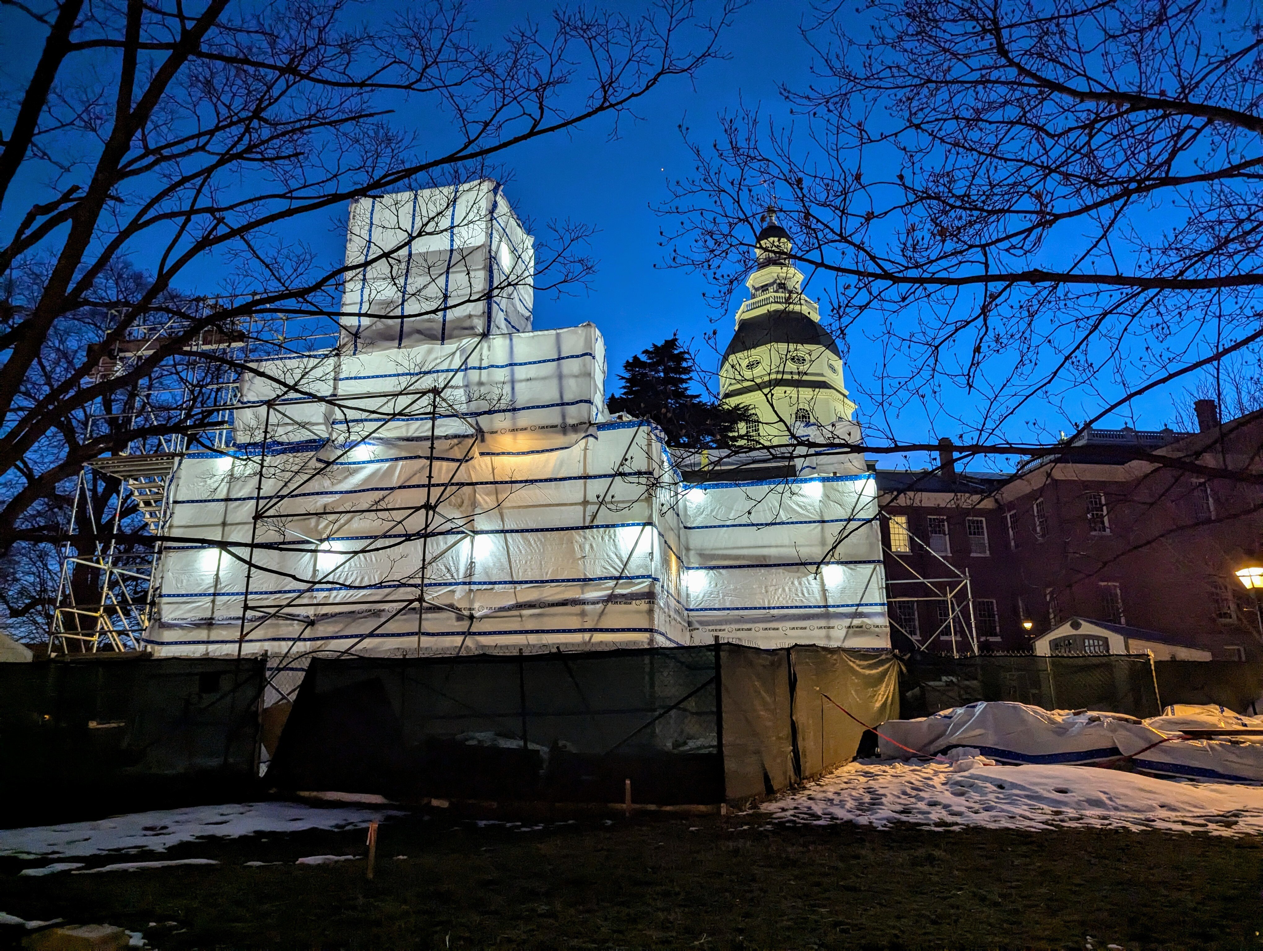 The Old Treasury Building lights up and early winter evening in Annapolis with the State House dome illuminated behind it. The state is restoring the colonial building.