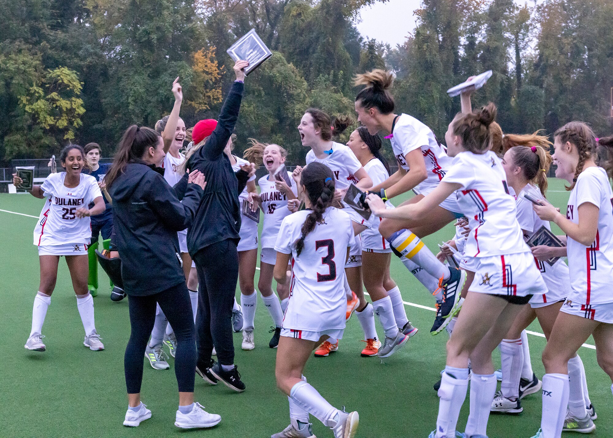 Dulaney celebrates as coach Meredith Lott (red hat) holds up the Baltimore County field hockey championship plaque. The 14th-ranked Lions defeated No. 11 Hereford in penalty strokes (2-1) at Towson University's field hockey complex.