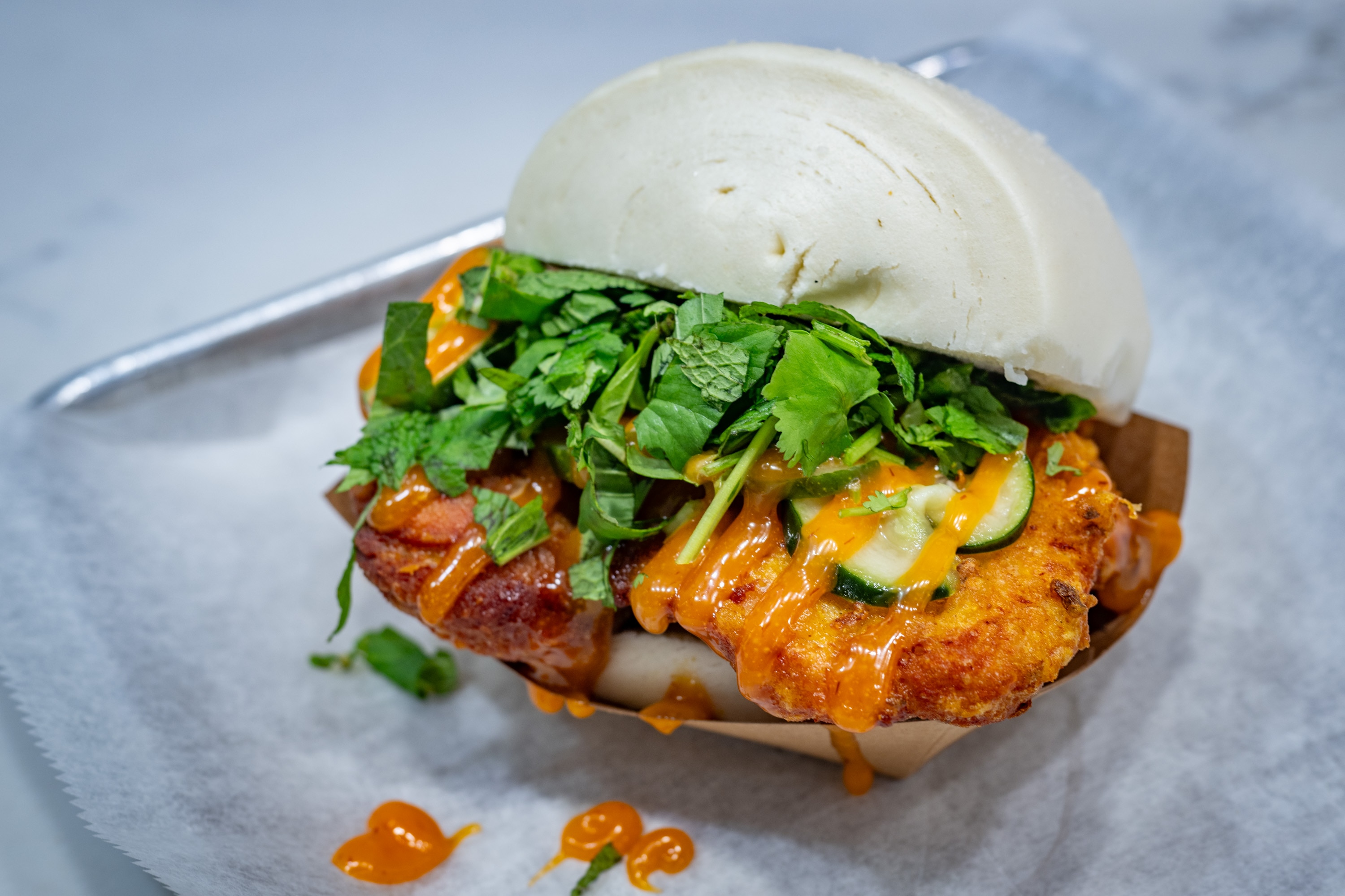 The Neighborhood Bird Bun from Ekiben features Taiwanese curry fried chicken thigh topped with spicy sambal mayo, pickles and fresh herbs.