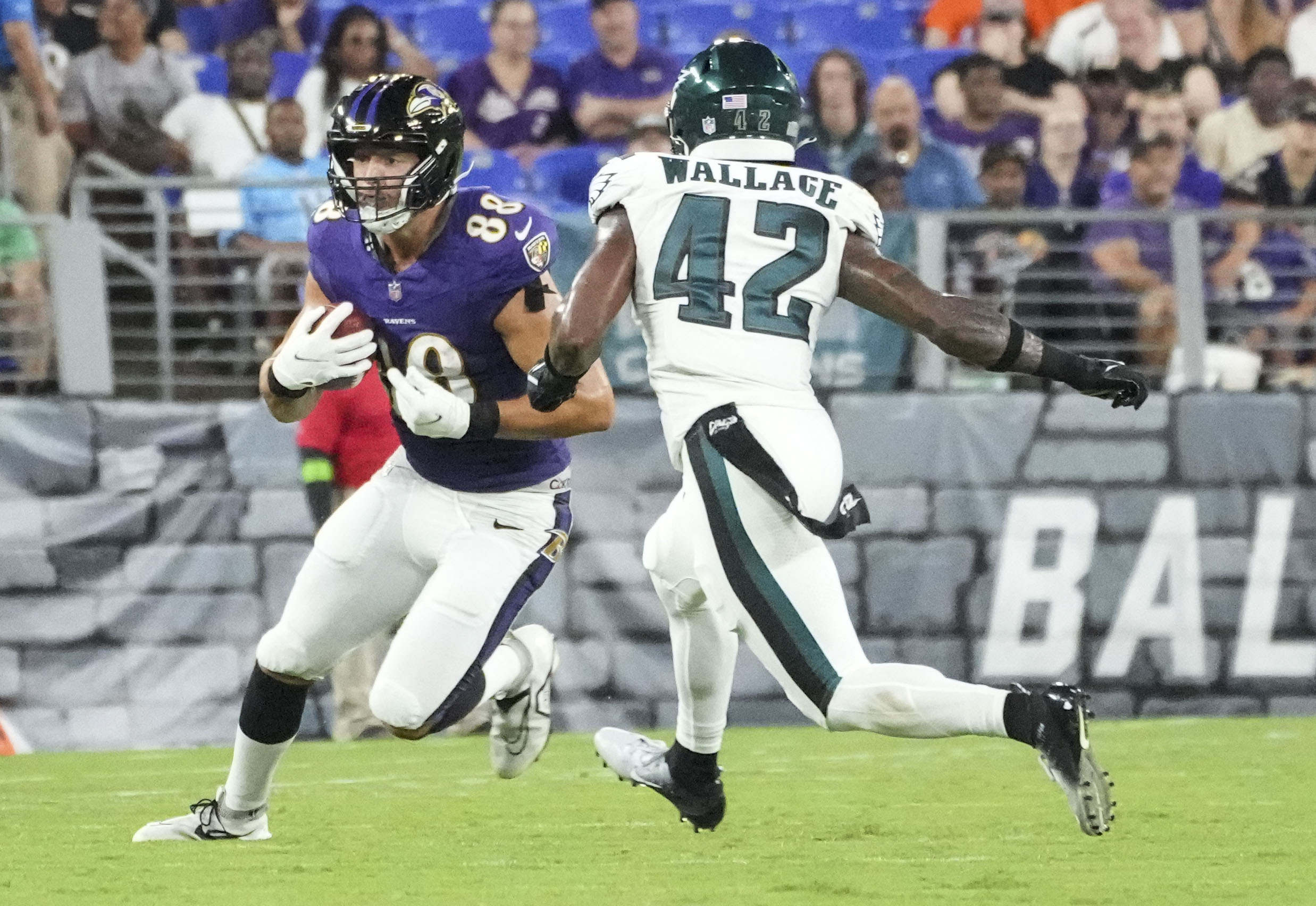 Ravens tight end Charlie Kolar runs after a catch as Eagles safety K'Von Wallace closes in Saturday night during Baltimore's 20-19 preseason win at M&T Bank Stadium.