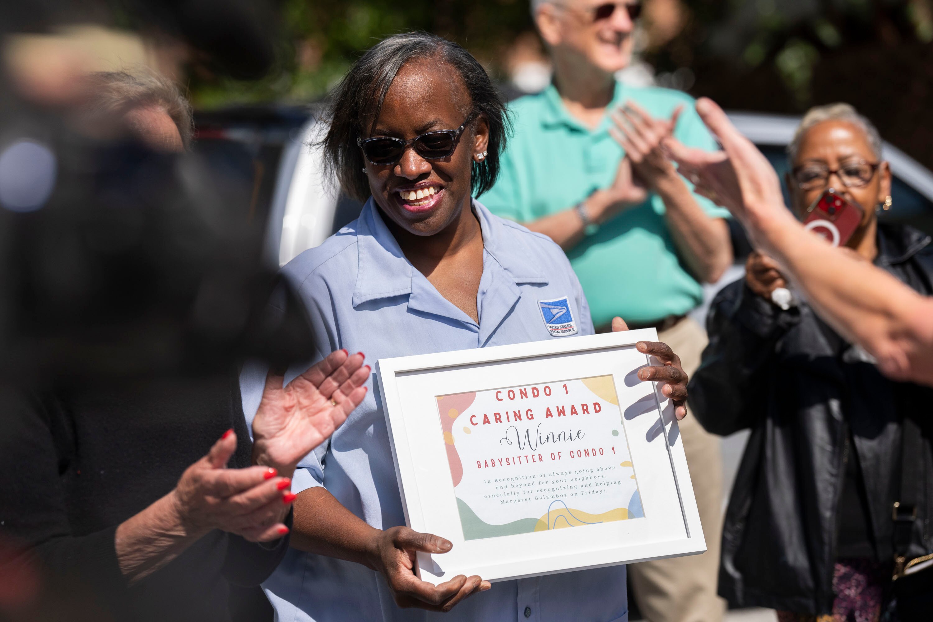 USPS mail carrier Winni Thompson is honored with a plaque from residents of North Baltimore’s Village of Cross Keys on Friday.